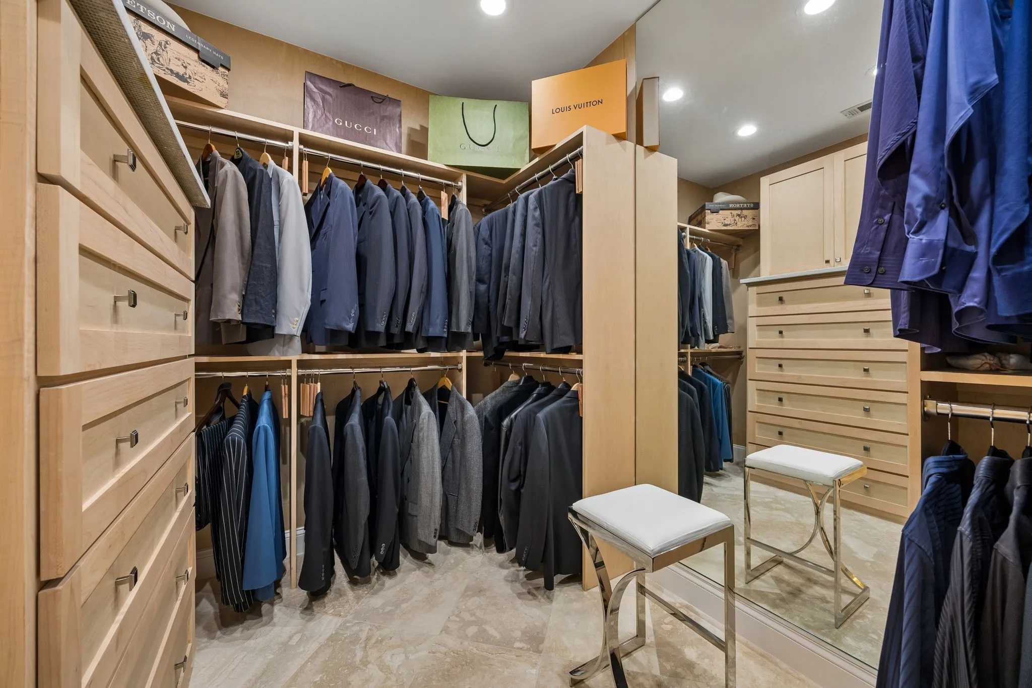 A luxurious extension of the primary suite, this renovated custom walk-in closet is designed to make organization effortless. Custom Maple cabinetry provides an abundance of hanging, complimented by a floor-to-ceiling bureau with extensive drawer storage, floor to ceiling mirror and recessed lights elevate the space.