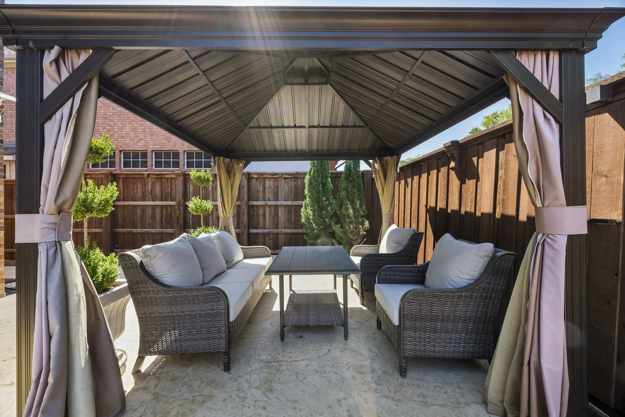 Covered cabana with comfortable seating creates a dedicated outdoor gathering space, perfect for enjoying the backyard and pool in the shade.
