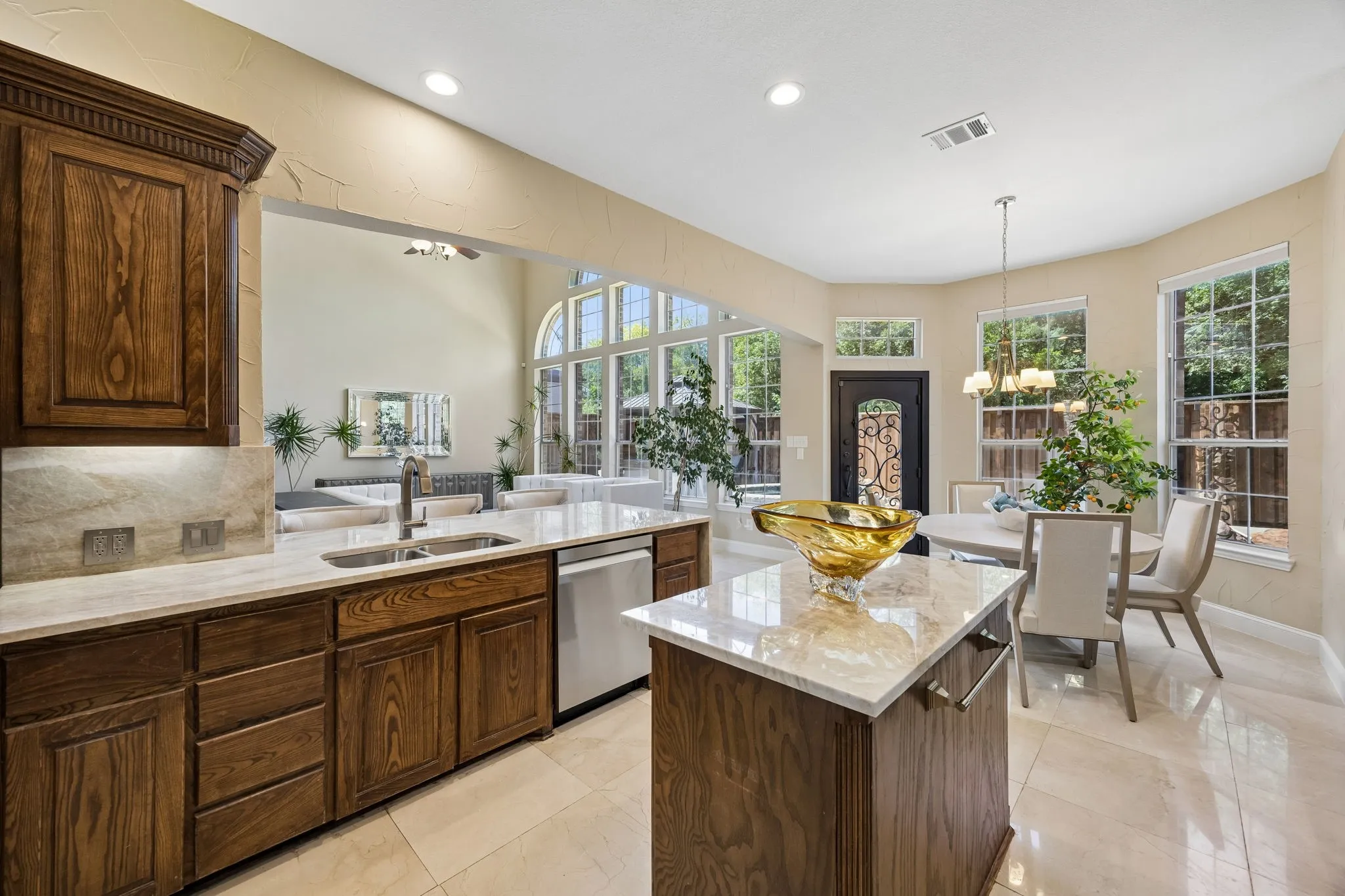 This view highlights the updated kitchen's seamless connection to the breakfast and living area, creating an inviting flow for relaxed gatherings and gracious hosting.  The abundant windows elevate the space while open sightlines showcase the impressive two-story living area beyond.