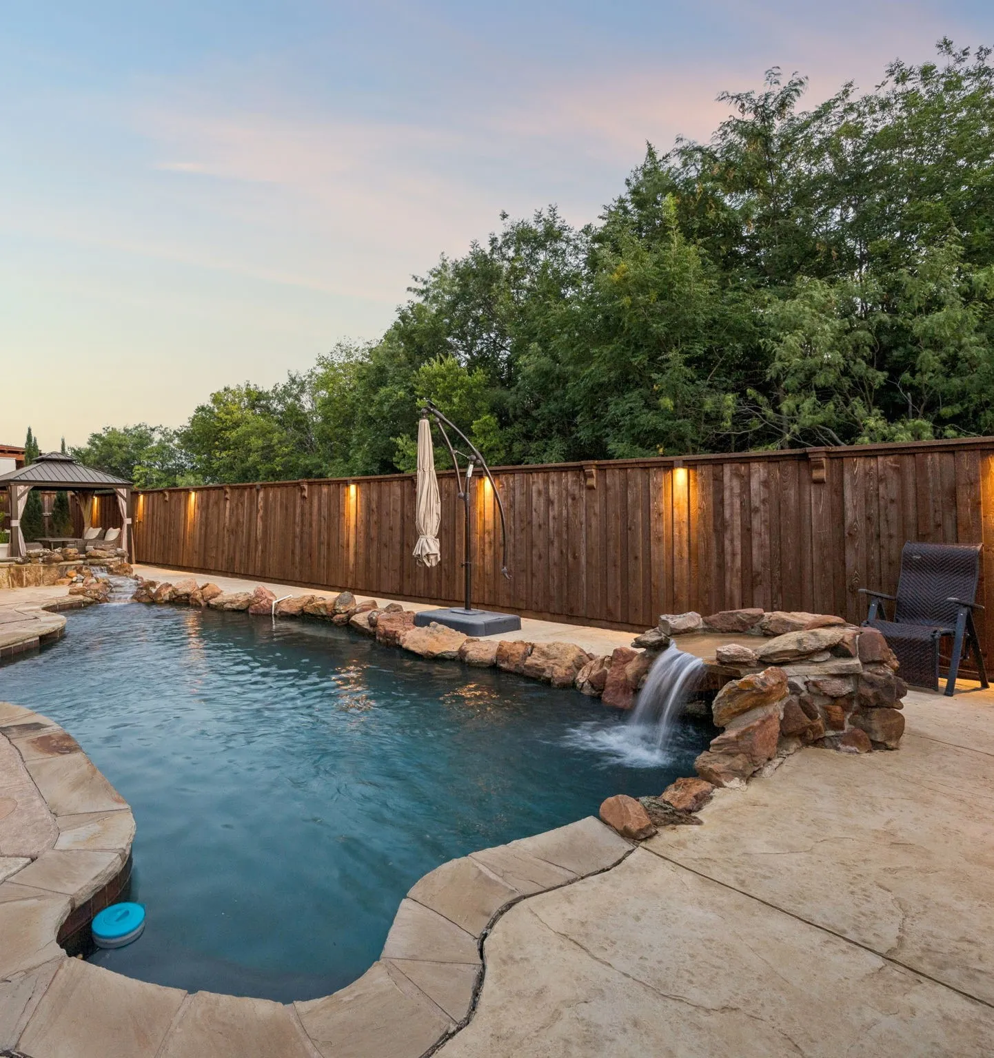 Twilight brings the backyard to life, with the sparkling pool, waterfall and warm accent lighting creating an ideal setting for evening entertaining and relaxed outdoor gatherings.