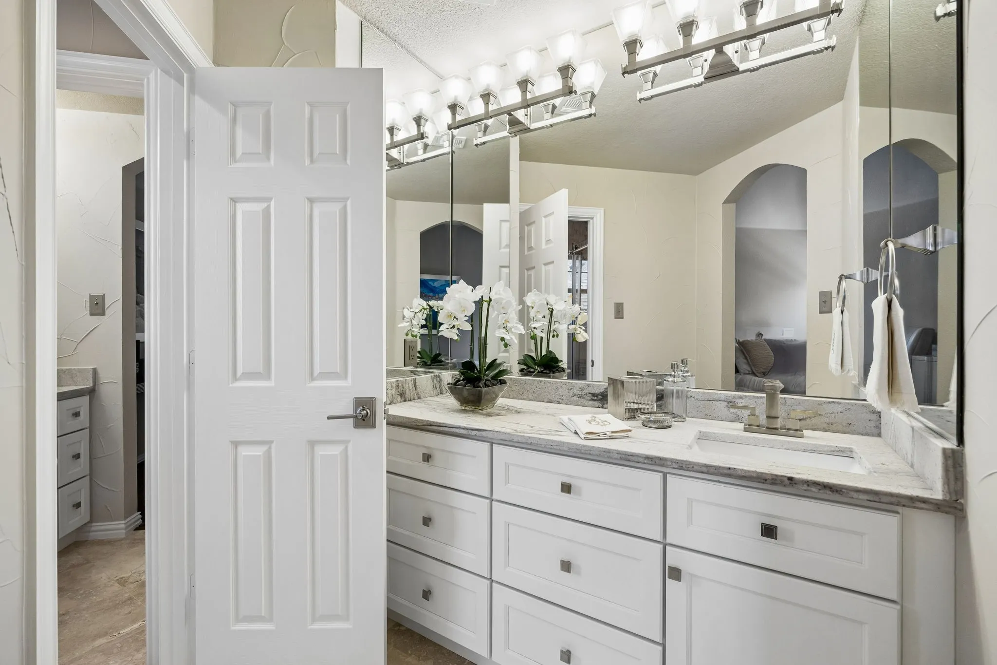  The well-appointed upstairs Jack and Jill bathroom offers spacious individual vanity areas for each secondary bedroom, featuring leathered natural stone countertops, travertine floors and generous storage.