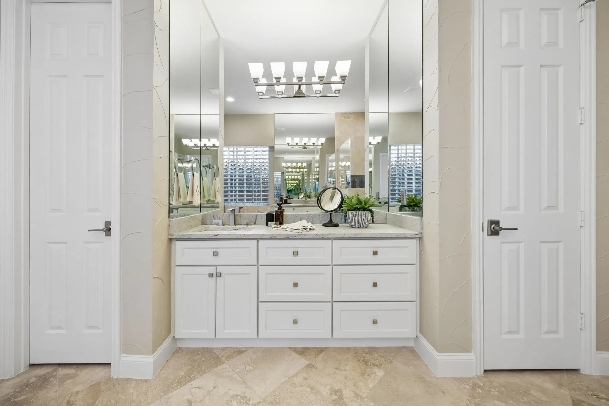 His and Her separate vanities in the primary bathroom allow for plenty of space to spread out.  Thoughtfully updated with an abundance of storage and beautiful leathered natural stone counter tops.