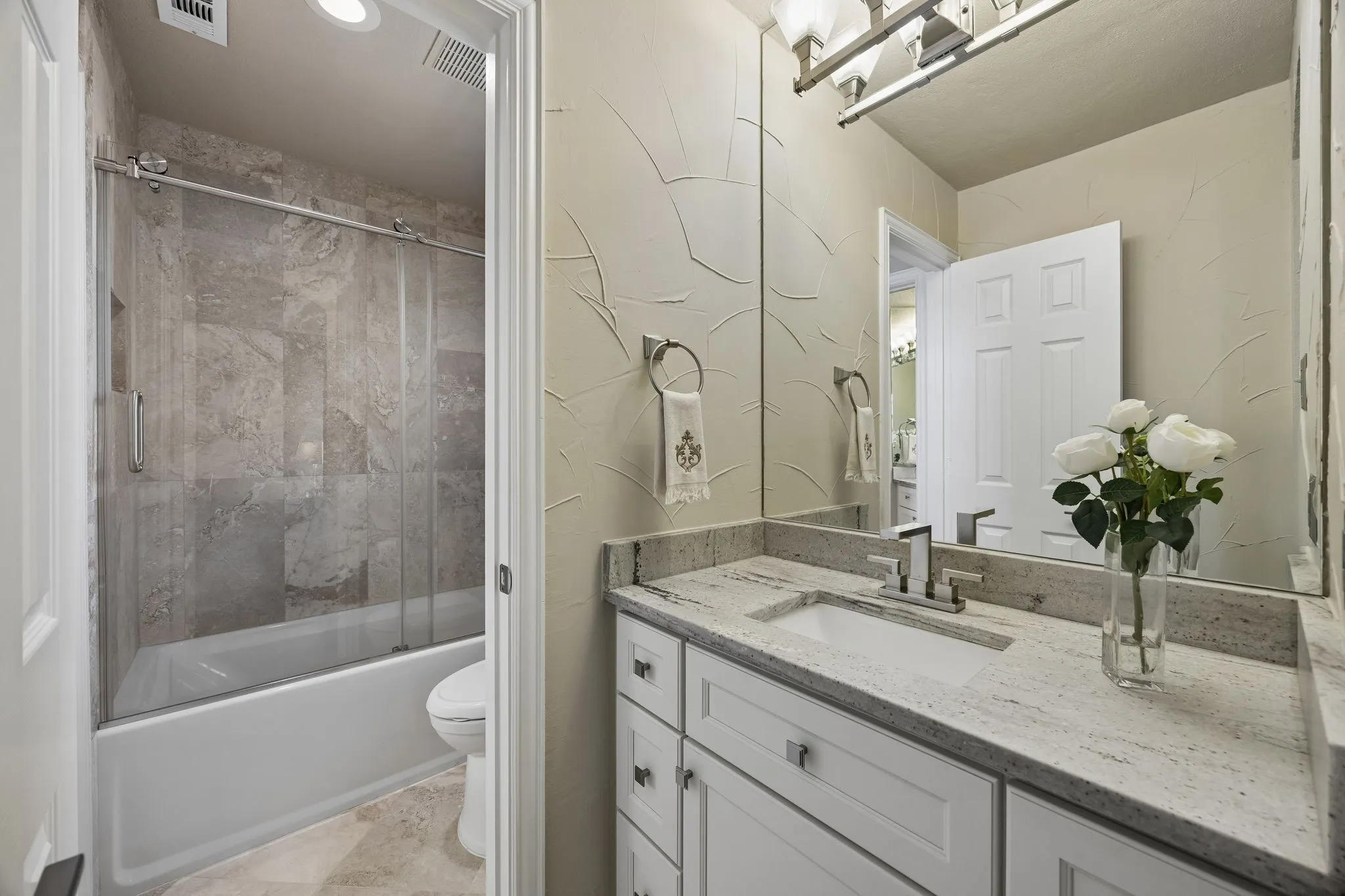 This Jack and Jill has a separate bath/shower/commode area that provides added privacy and convenience, while travertine flooring and thoughtfully selected details complement the home's elevated design.