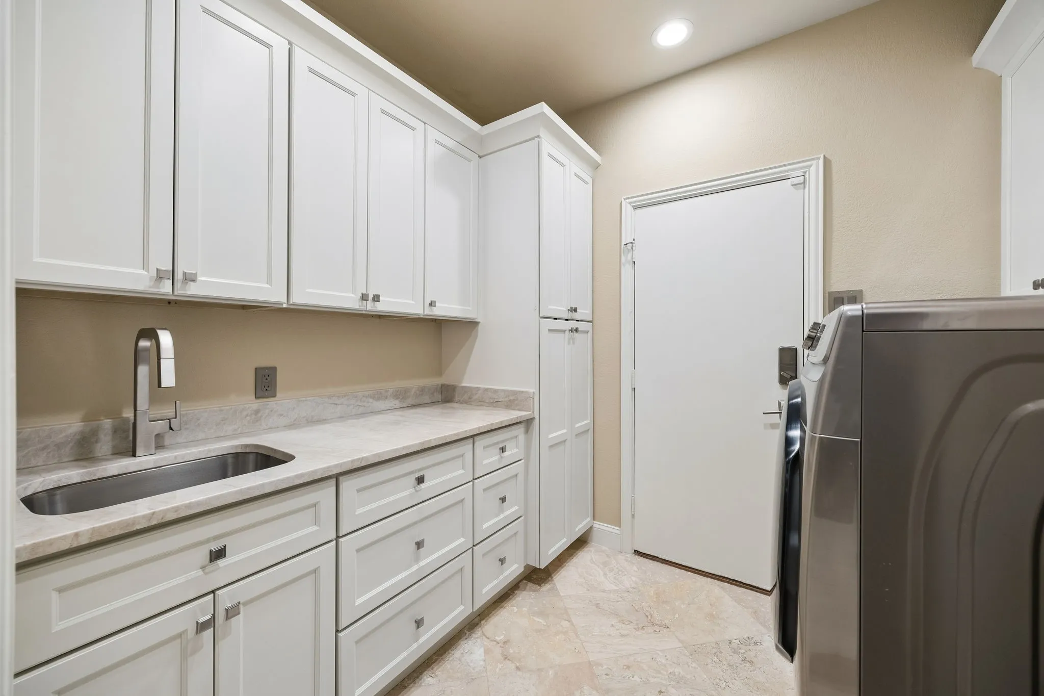 Carefully updated with no detail spared. This beautifully renovated laundry room combines style, storage and everyday functionality. Natural stone floors, Taj Mahal quartzite countertops and more.