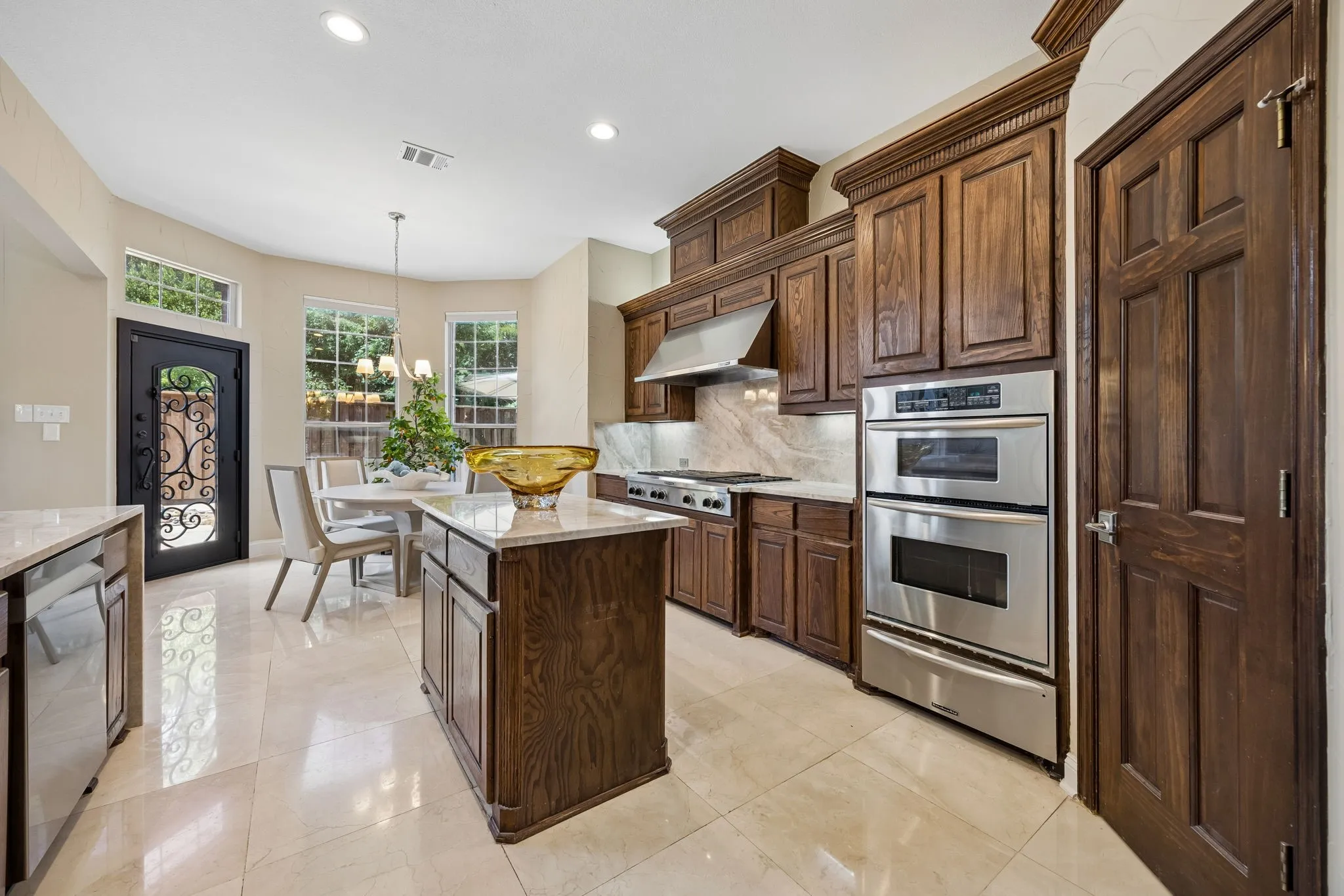 Spacious kitchen blends warmth and functionality with rich Oak cabinetry, natural stone floors and Taj Mahal Quartzite countertops, stainless steel appliances and a generous center island.