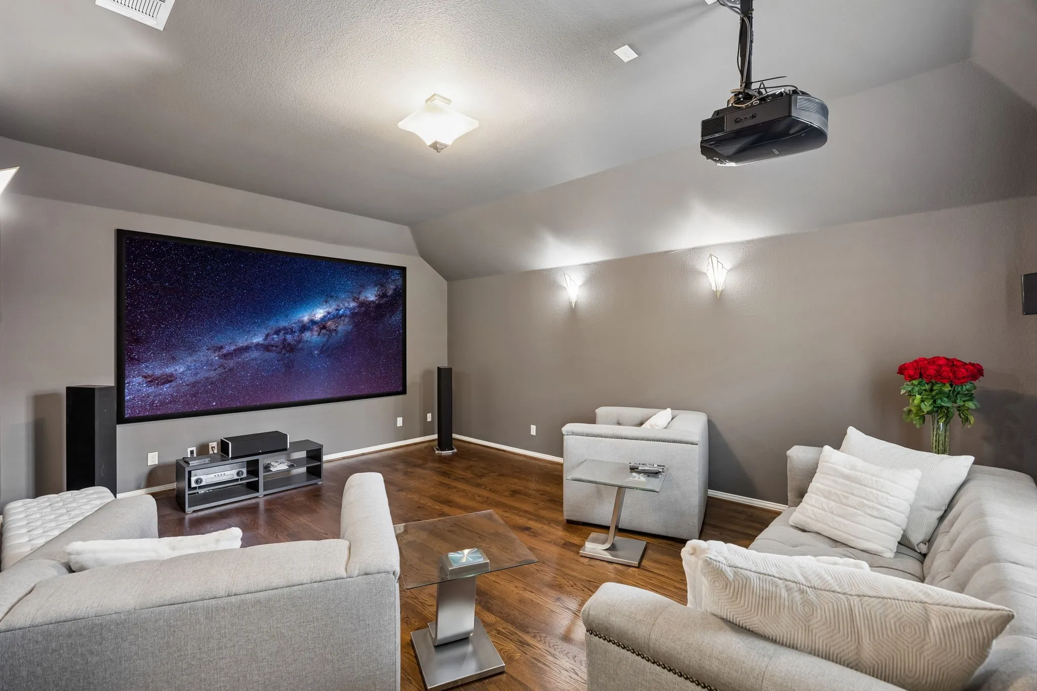 Step down into this inviting media room, designed for an immersive at home viewing experience with an impressive 150-inch screen, built in speakers and ceiling mounted projector.  Rich solid hardwood floors, a spacious seating area with soft ambient lighting to create a comfortable setting for movie nights, sporting events and entertaining.