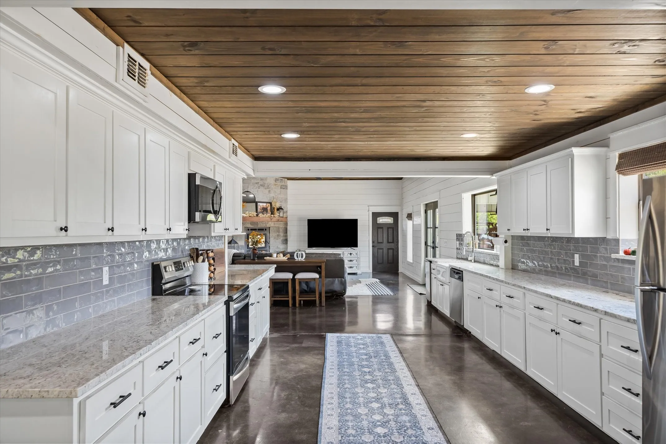 Bright kitchen with granite counters and tiled backsplash is ready to serve up the garden veggies