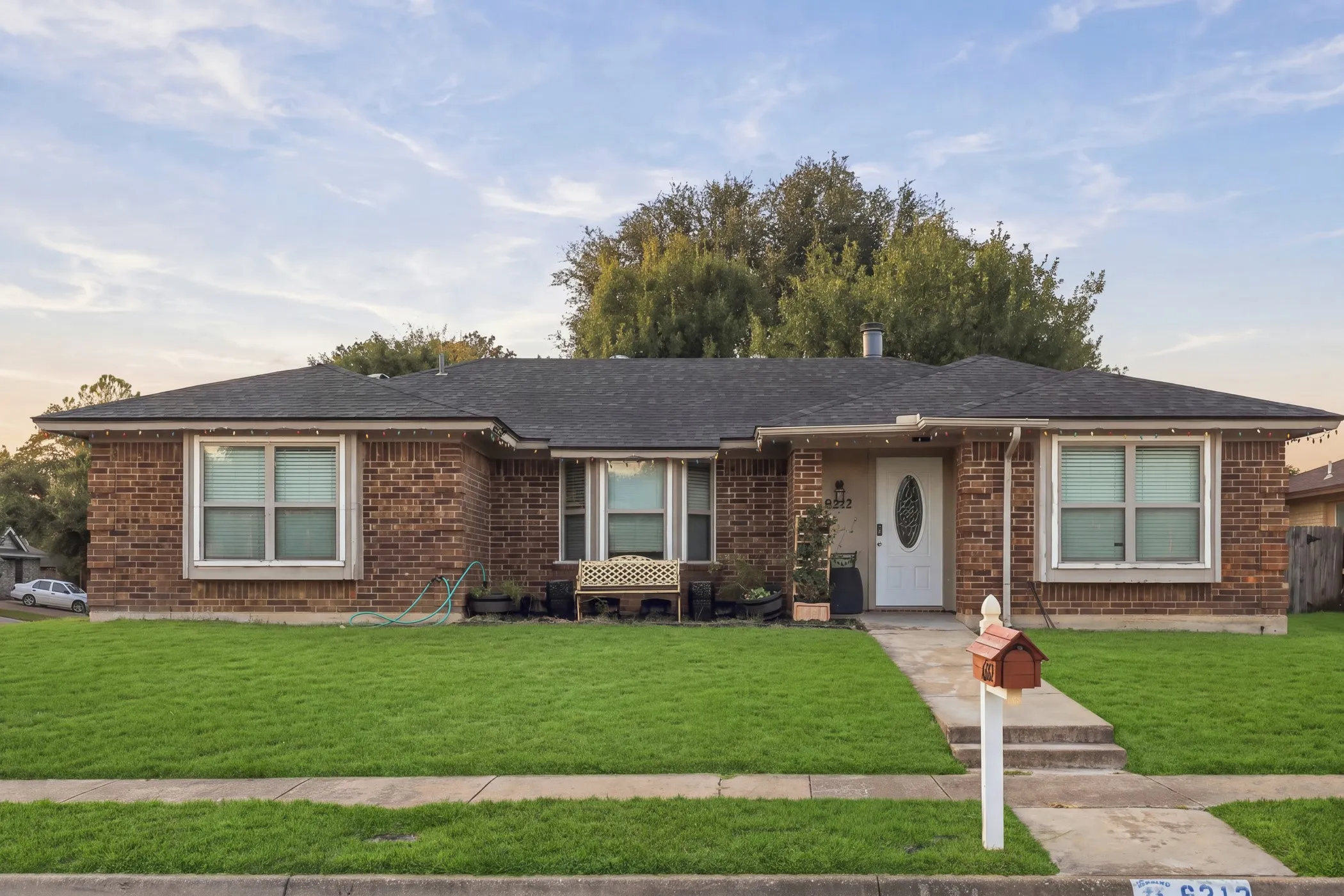 Brick exterior with a dark shingle roof, complemented by a front lawn and a concrete walkway