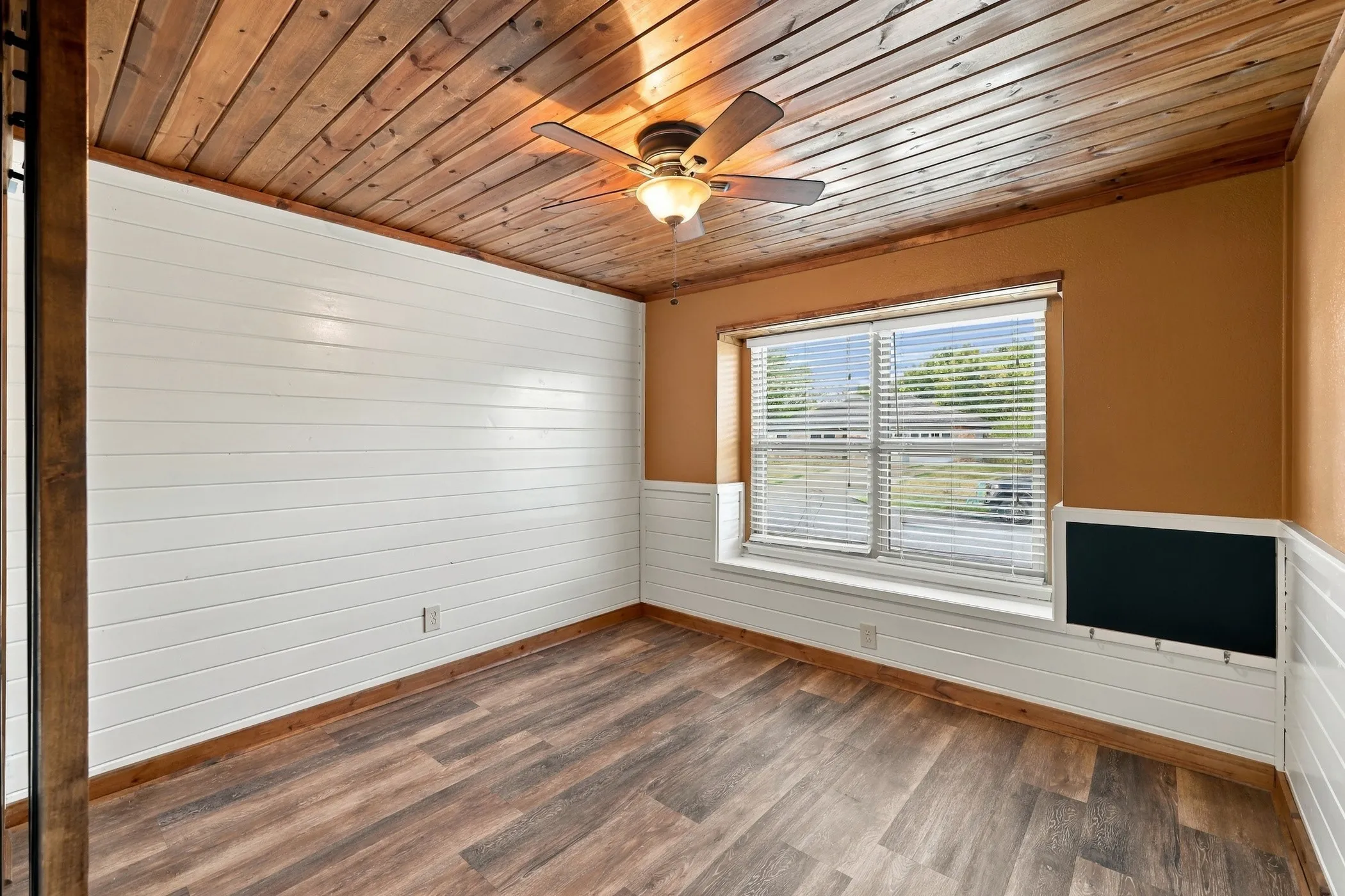 Wood-finish ceiling, wood-finish flooring, white shiplap wainscoting, and a ceiling fan with integrated lighting