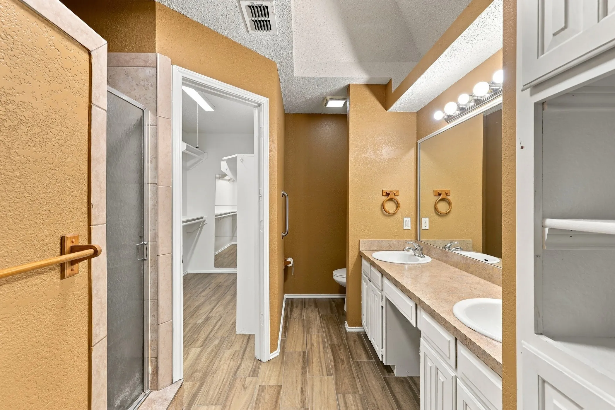 Bathroom featuring a double vanity with integrated sinks, a built-in shower, wood-finish flooring, and recessed lighting