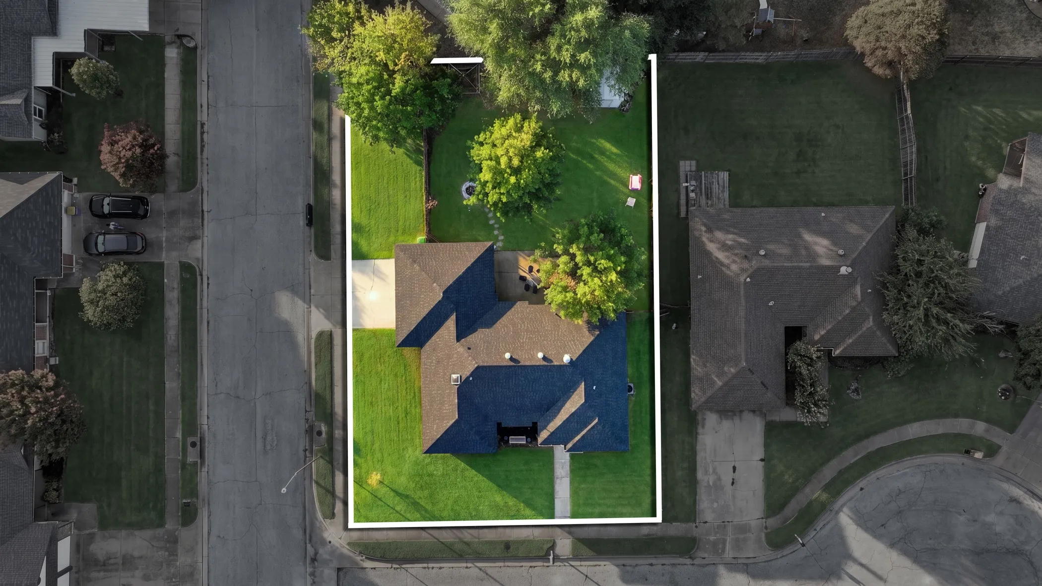 House with a dark roof, surrounded by green lawn and mature trees