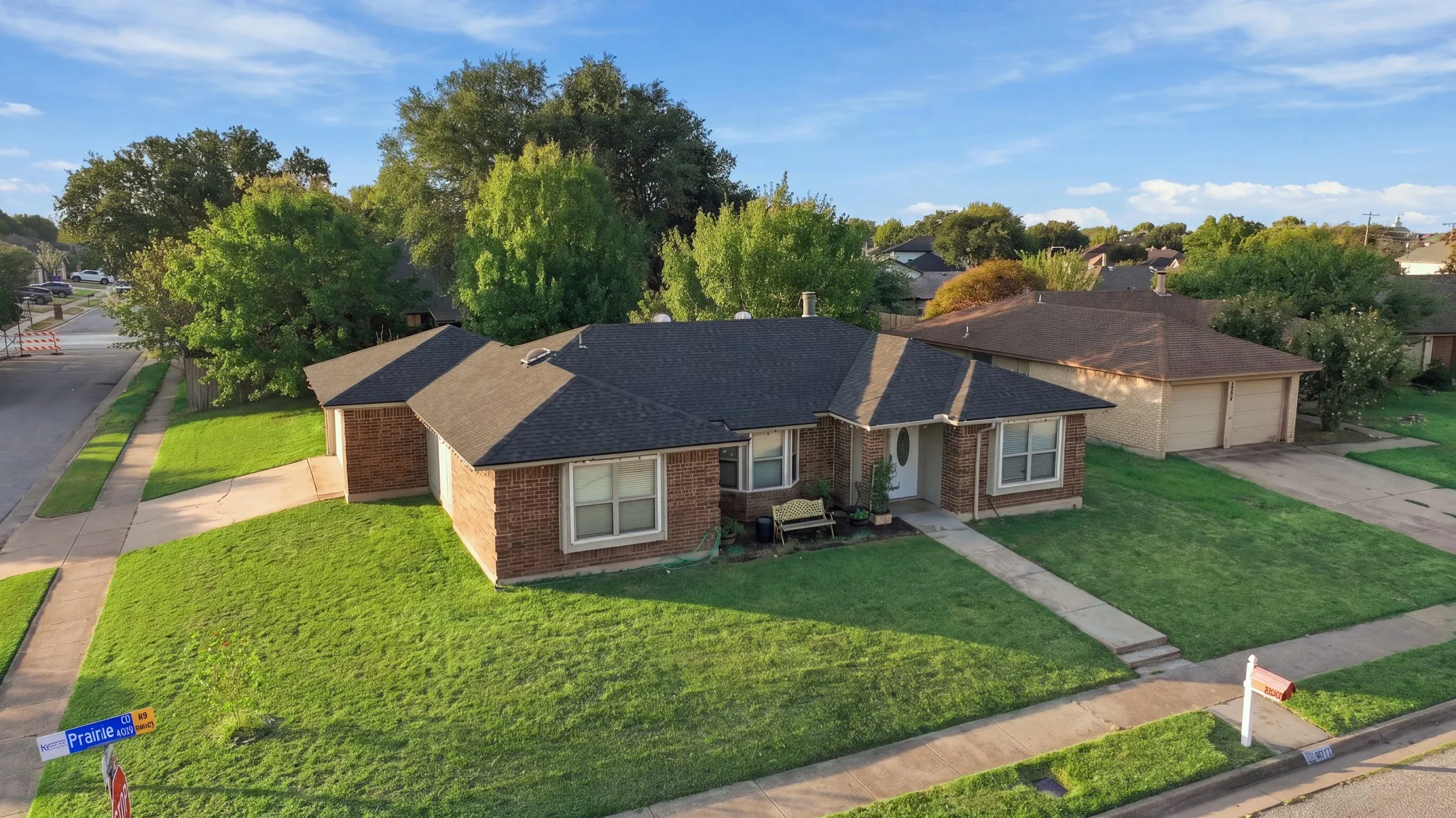 Brick exterior with a dark shingle roof, concrete driveway, and front sidewalk