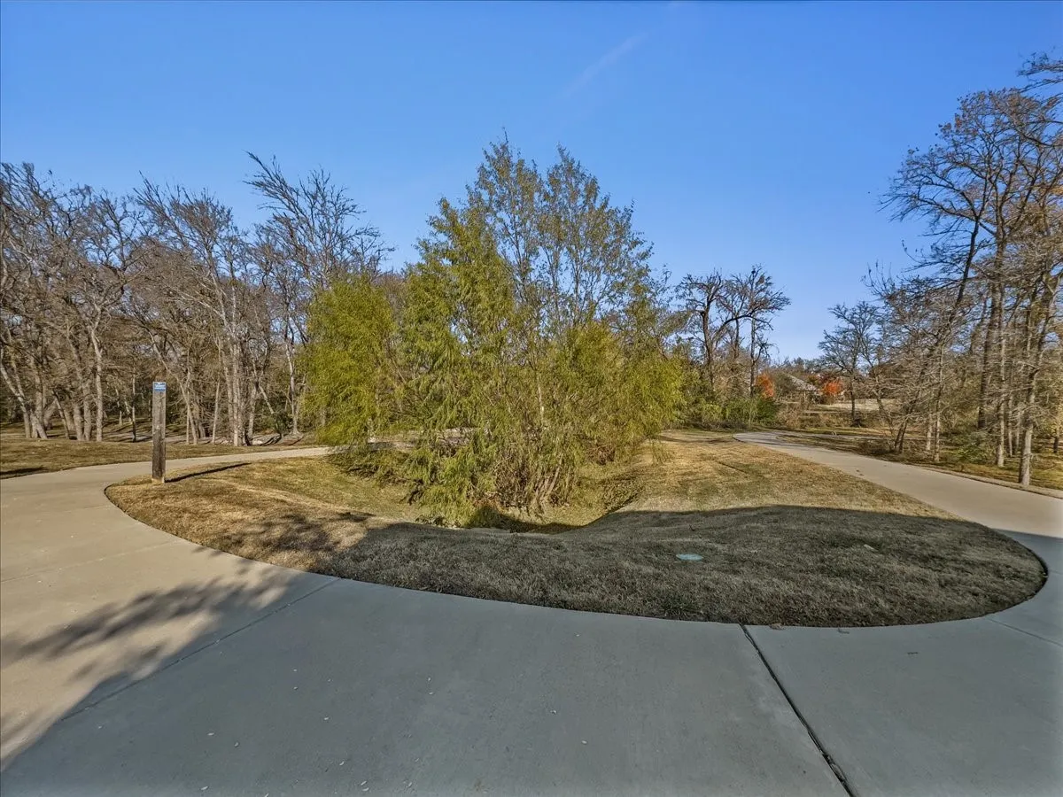 Paved pathway with surrounding grassy areas and mature trees