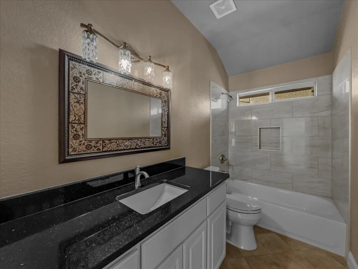Vanity with a black speckled countertop, undermount sink, and chrome faucet