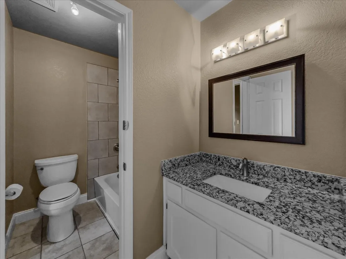 Vanity with a granite-style countertop, white cabinetry, and an undermount sink
