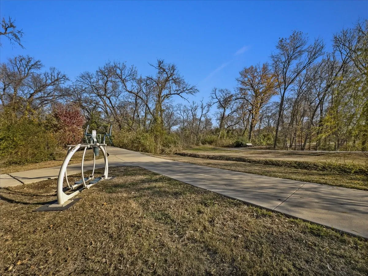 Paved pathway bordered by natural landscaping and mature trees