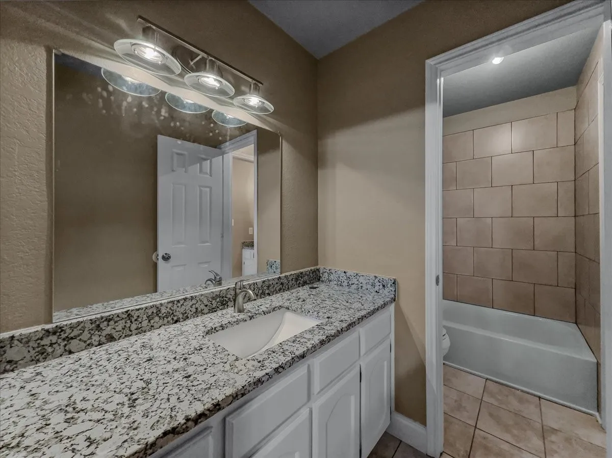 Vanity with granite-style countertop, undermount sink, and brushed nickel faucet