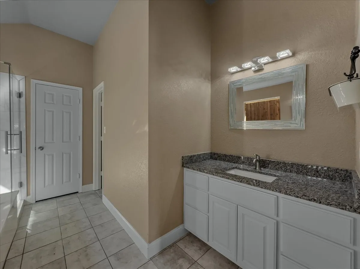 White vanity with a built-in sink, granite countertop, and polished chrome faucet