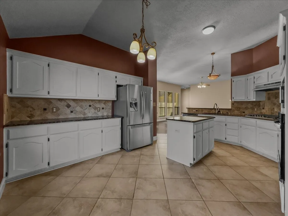 Spacious kitchen with white cabinetry, dark countertops, and a tiled backsplash