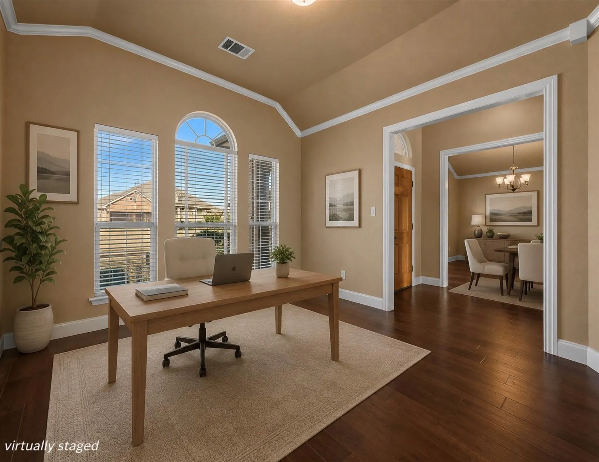 Vaulted ceiling with crown molding, dark wood-finish flooring, three windows including an arched window, and an open doorway leading to another room