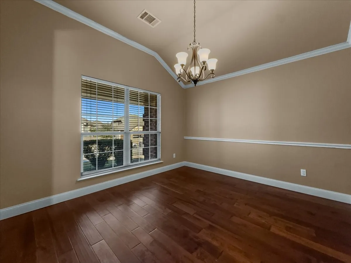 Vaulted ceiling, crown molding, chair rail molding, wood-finish flooring, and a multi-pane window