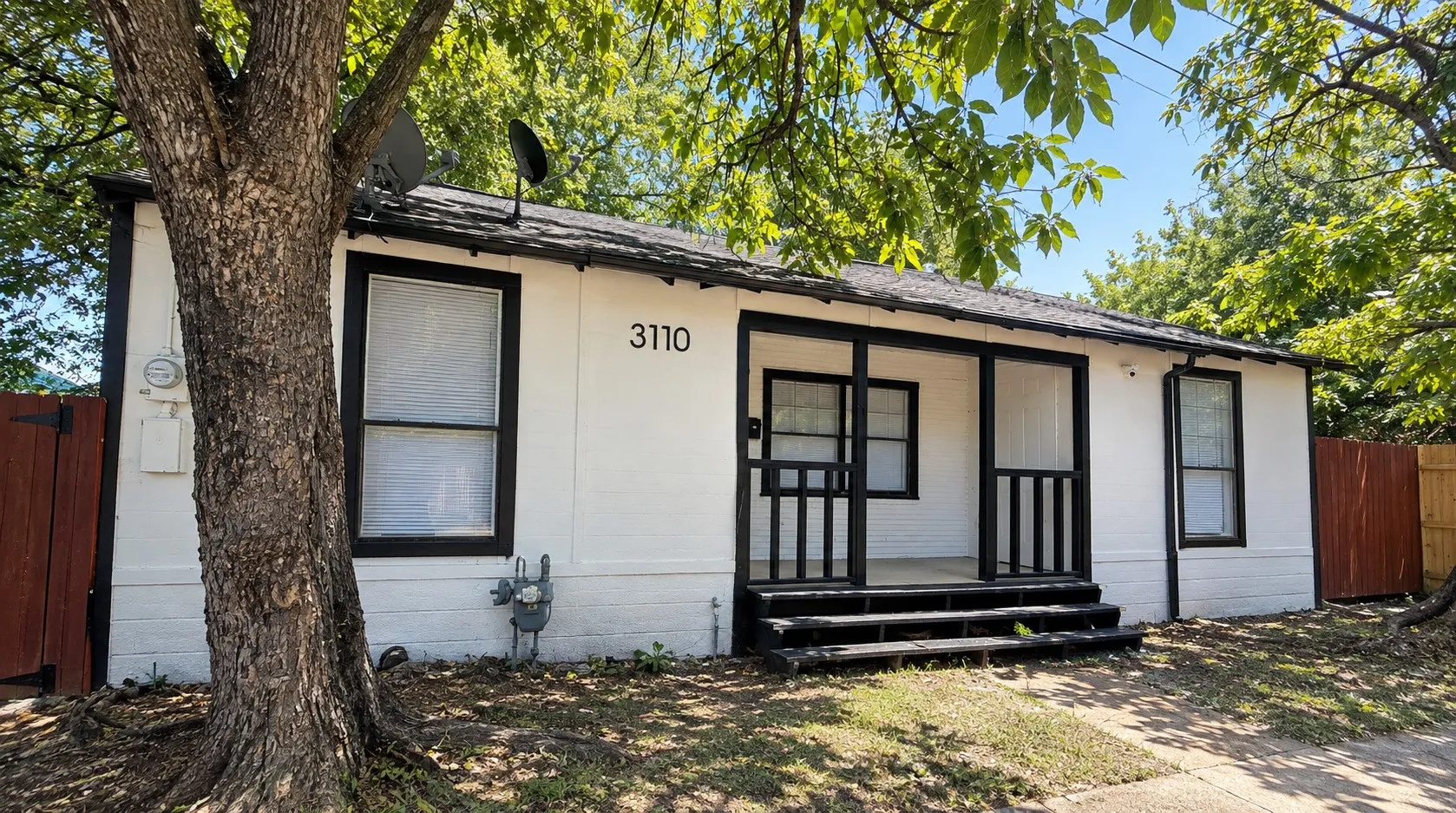 White exterior with black trim, covered front porch, and an asphalt shingle roof