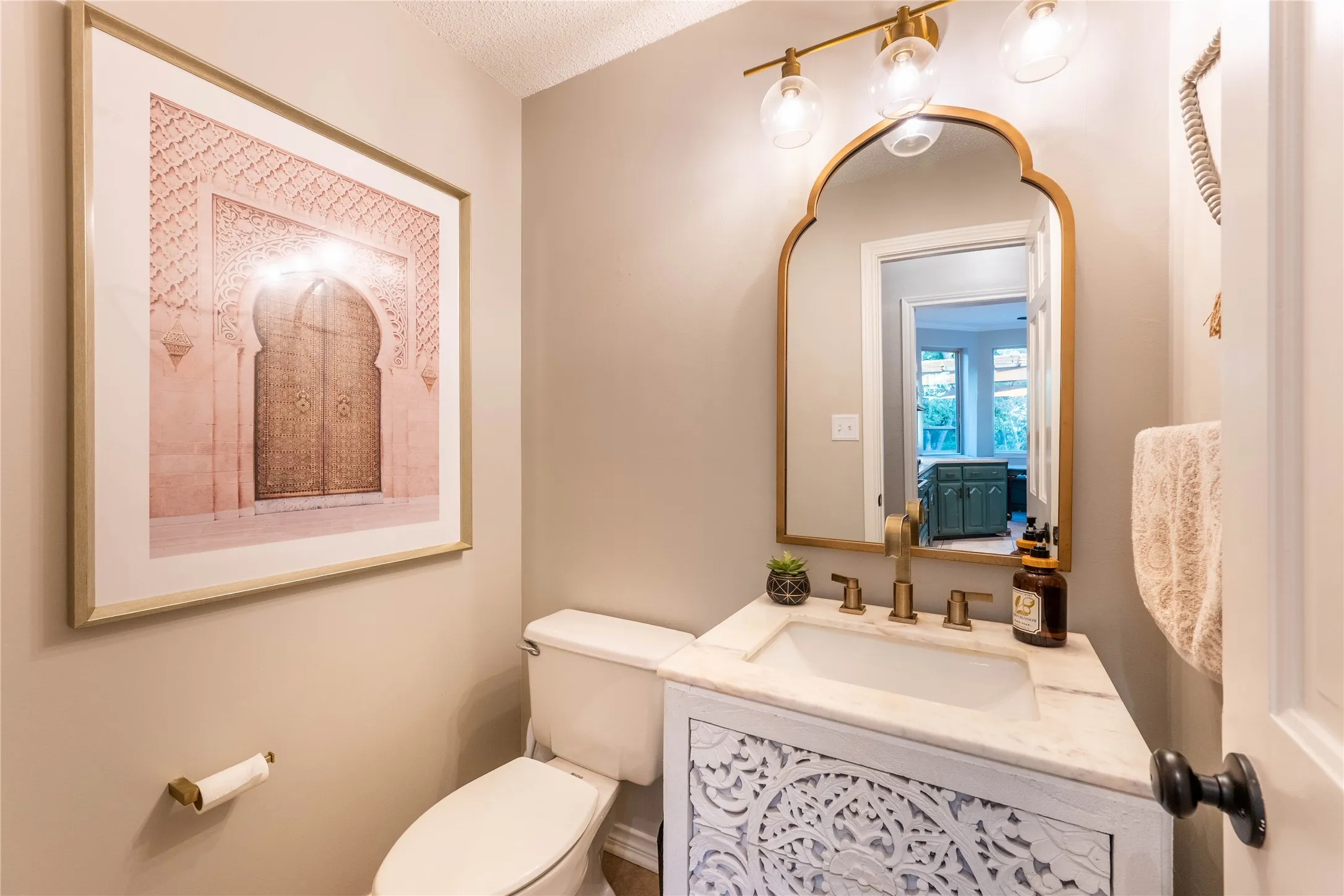 White vanity with carved wood-finish detailing, integrated sink, and stone-finish countertop
