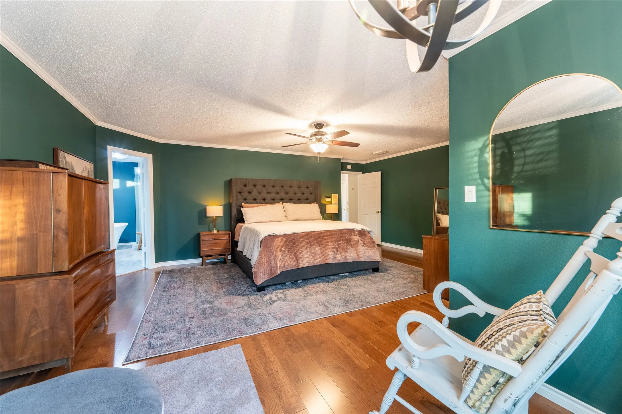 Hardwood flooring, ceiling fan, crown molding, and a doorway leading to an additional space