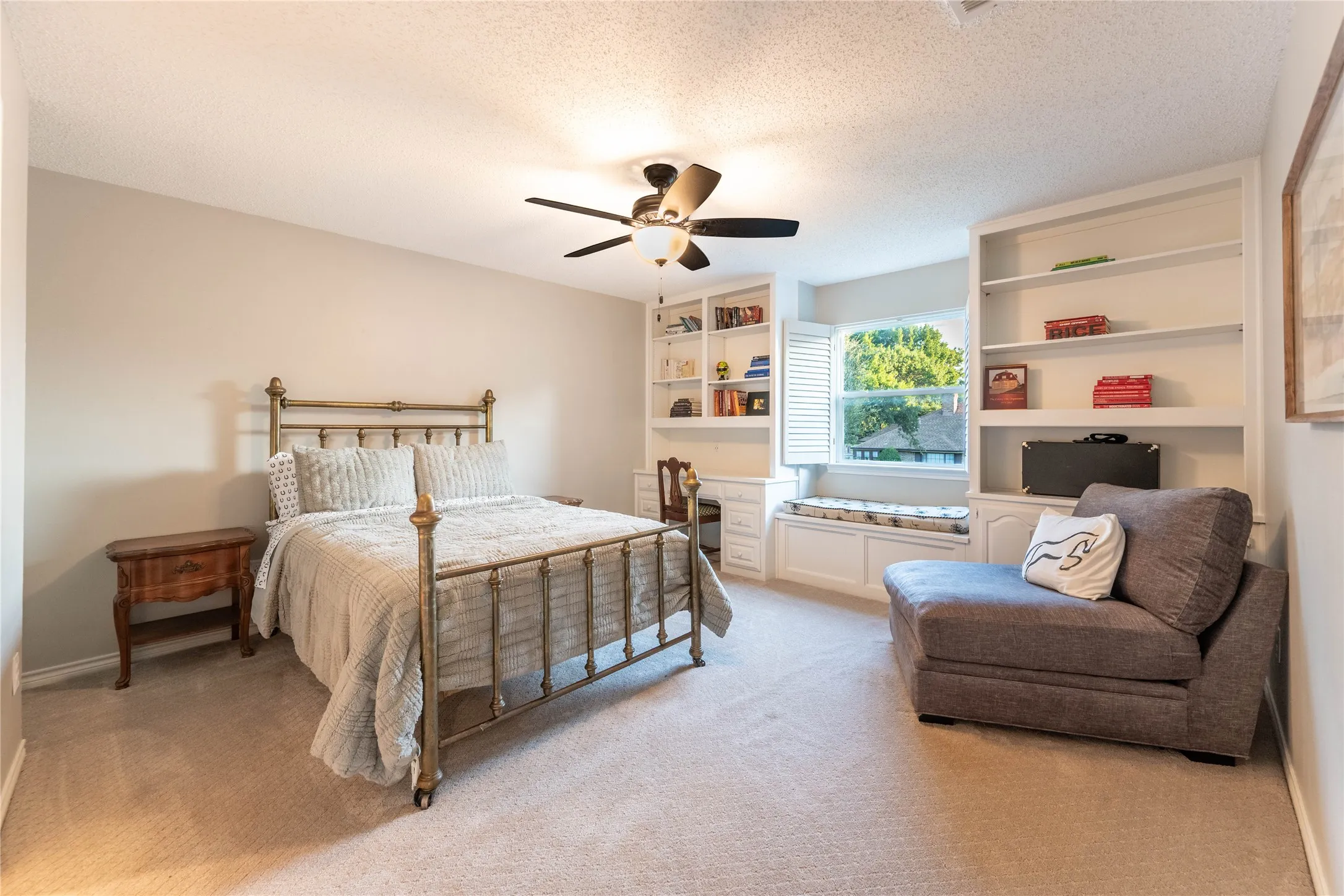 Built-in shelving, window seating with storage, ceiling fan, and light neutral wall color