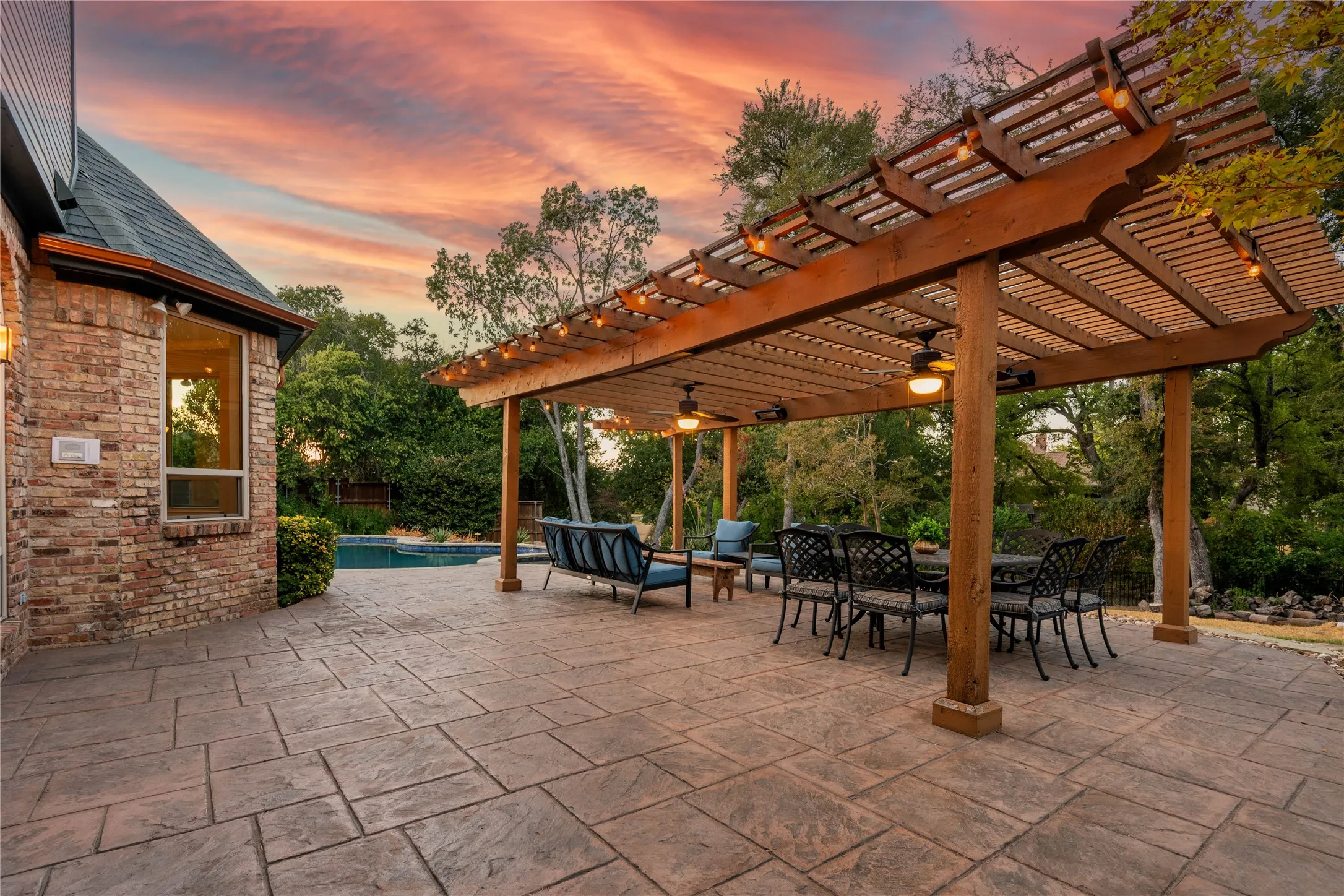 Stamped concrete patio with an expansive wood pergola featuring built-in lighting and ceiling fans