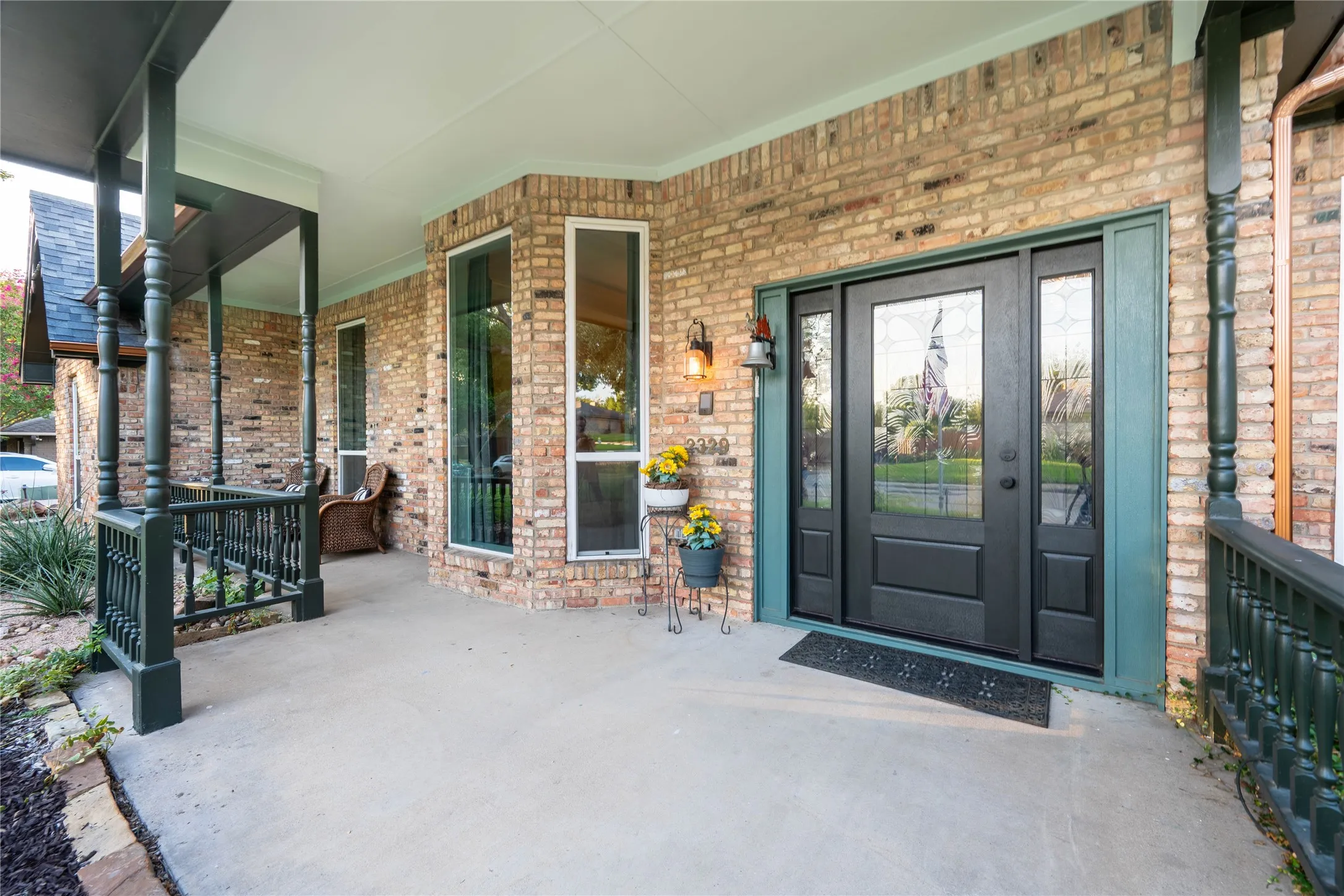 Brick exterior with a covered porch, decorative porch columns, and a dark-paneled entry door with sidelights