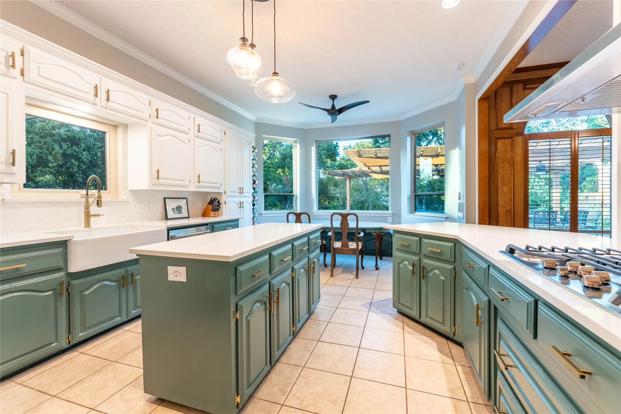 Expansive kitchen with a large island, white countertops, built-in gas range, and a farmhouse sink