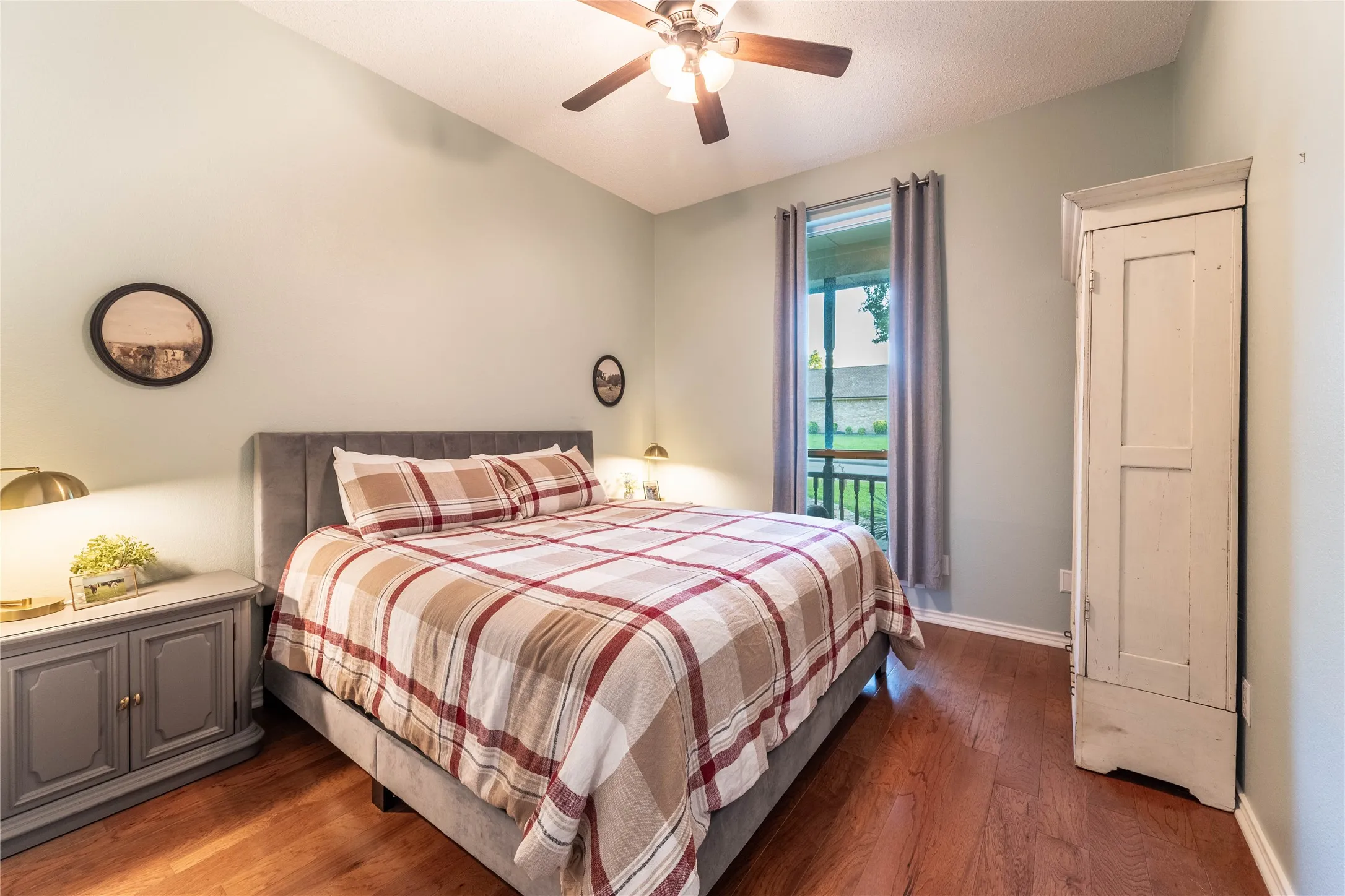 Vaulted ceiling featuring a ceiling fan, wood-finish flooring, and a window with outdoor porch access