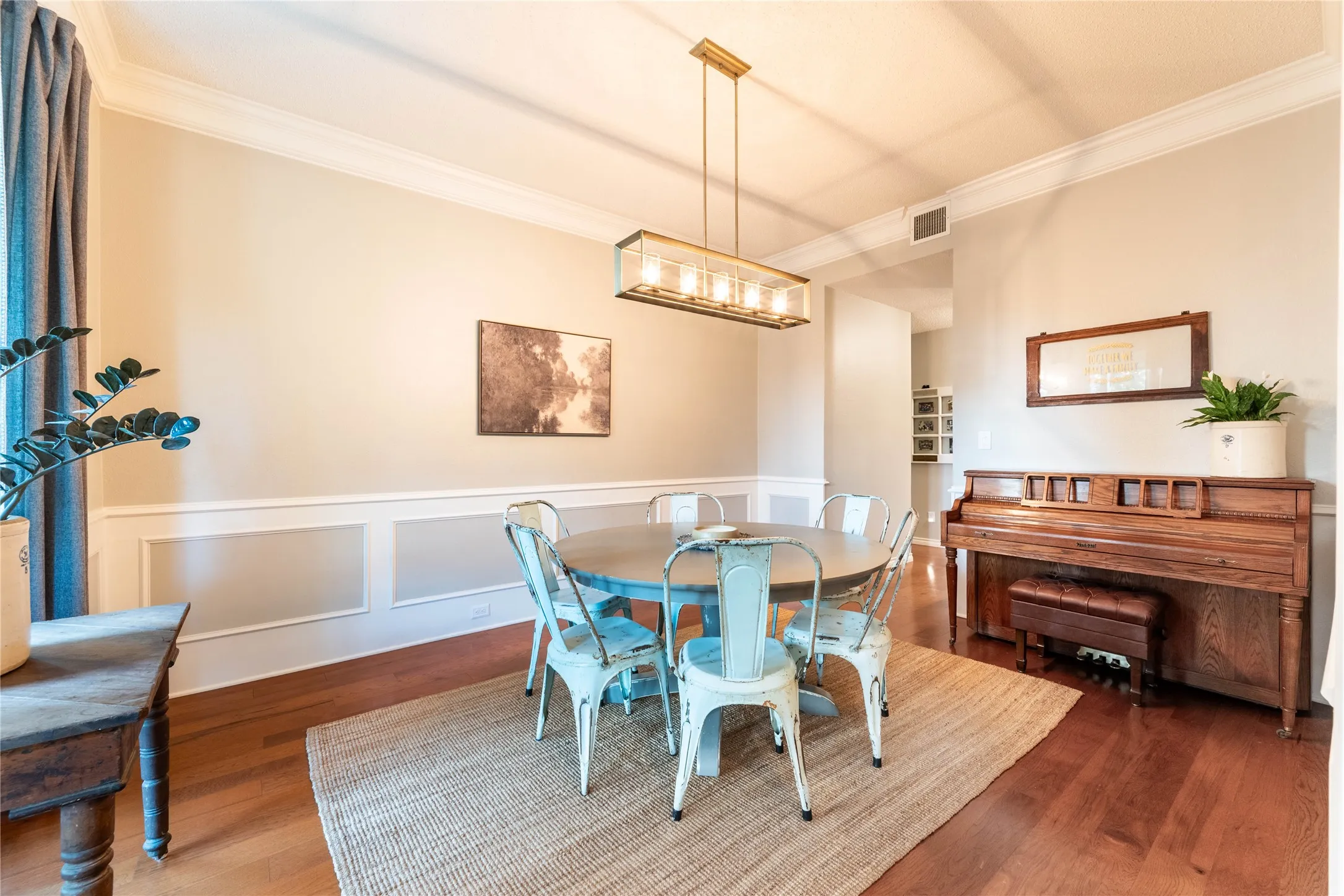 Hardwood flooring, crown molding, wainscoting, and a linear chandelier