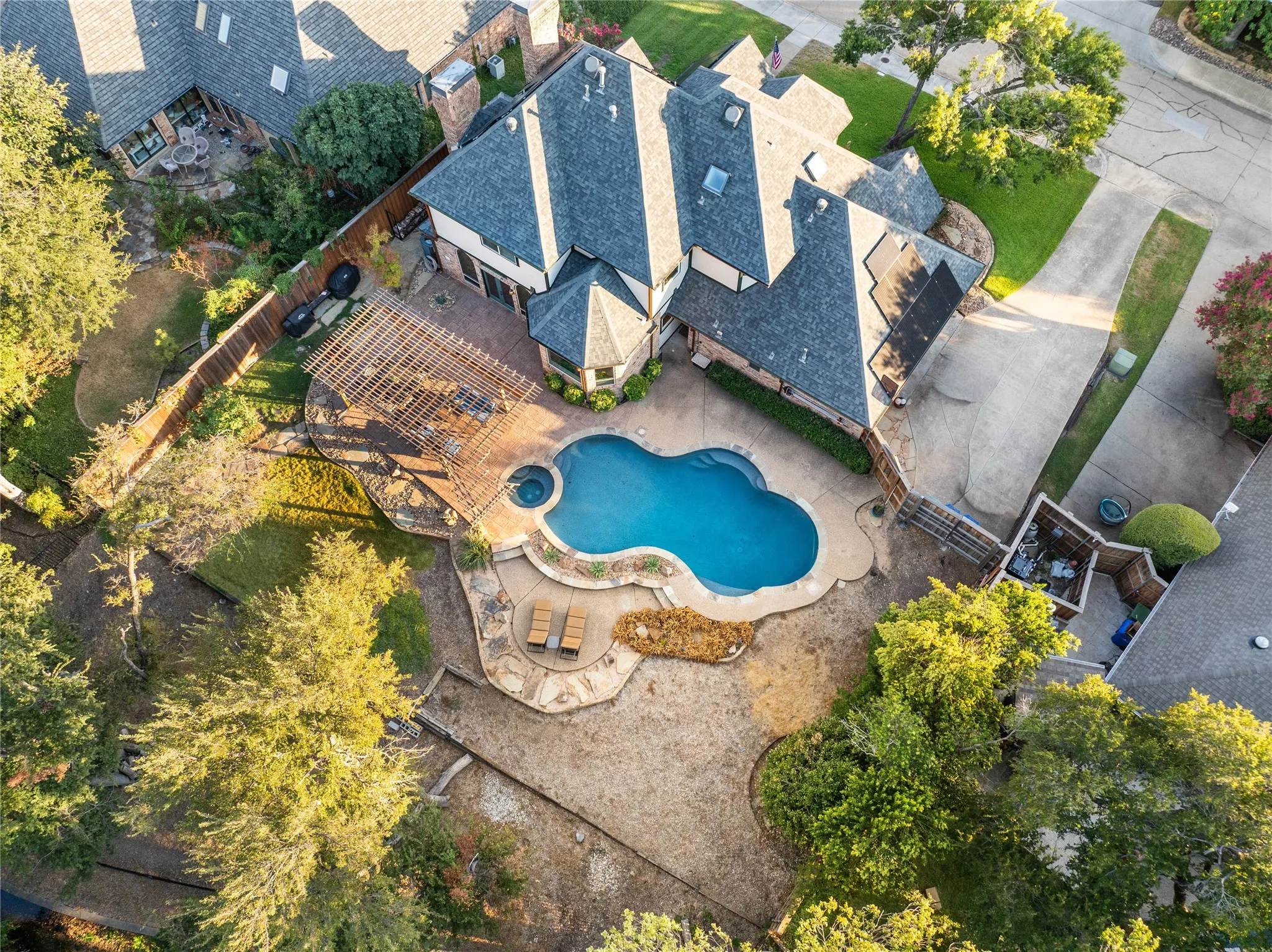 Backyard oasis featuring a free-form swimming pool, integrated spa, and expansive stone patio