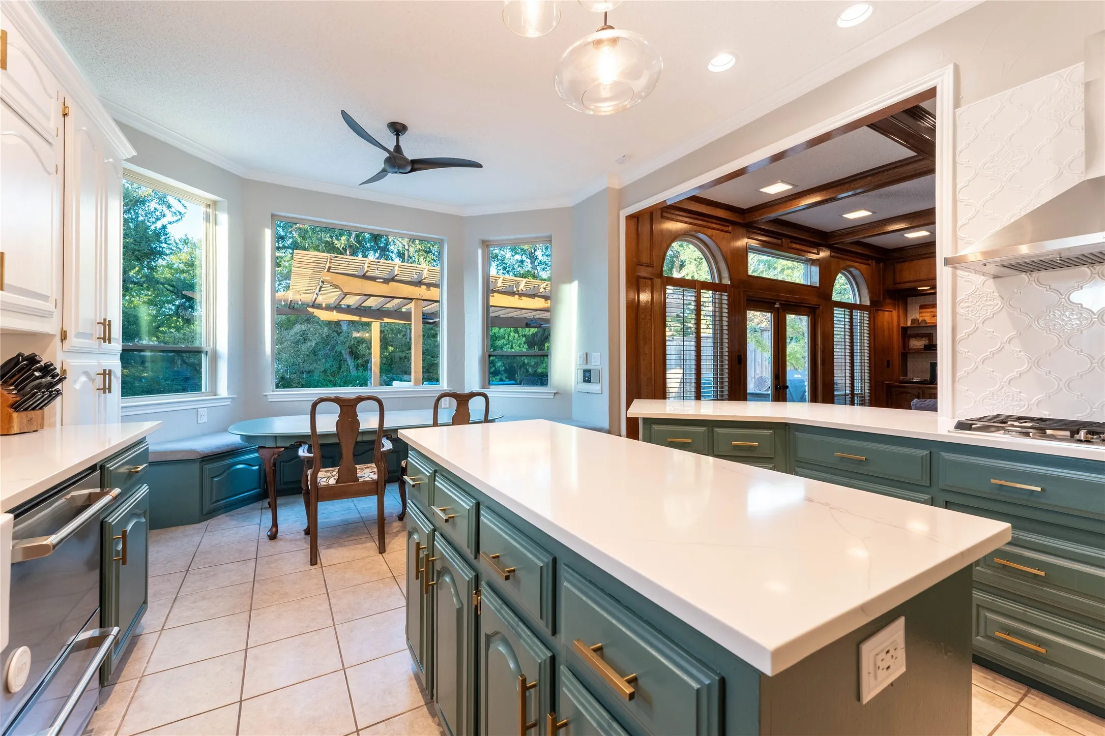 Kitchen featuring white countertops, teal cabinetry, a built-in banquette, and stainless steel appliances