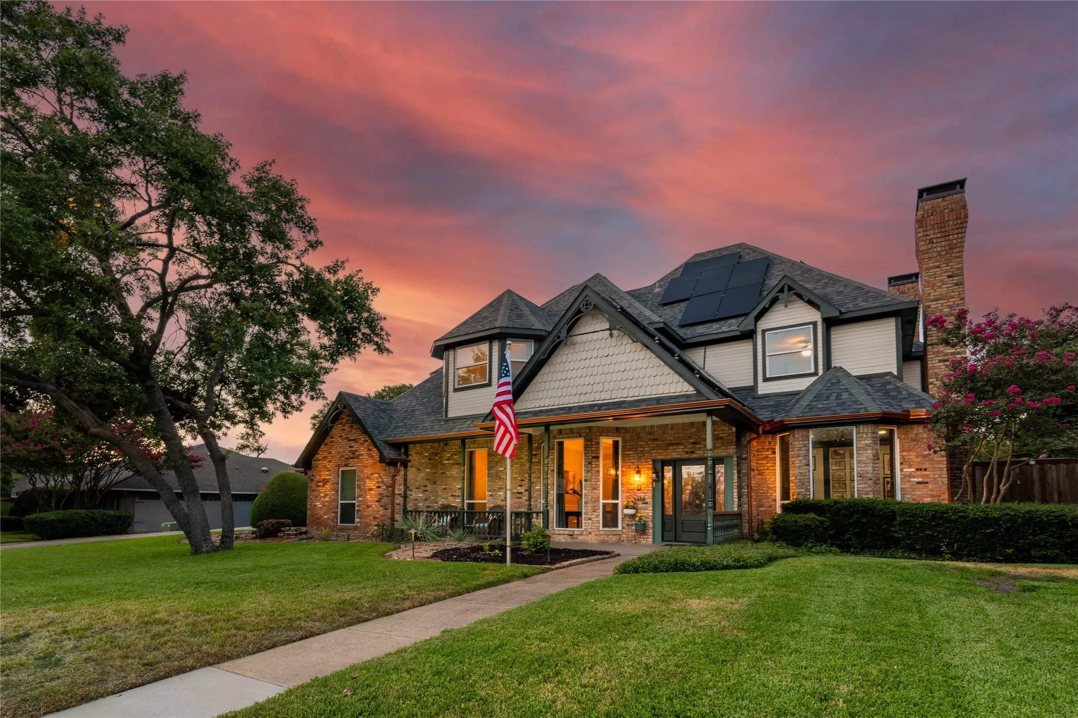 Two-story home featuring a brick and siding facade, covered front porch, multi-pane windows, and a prominent brick chimney