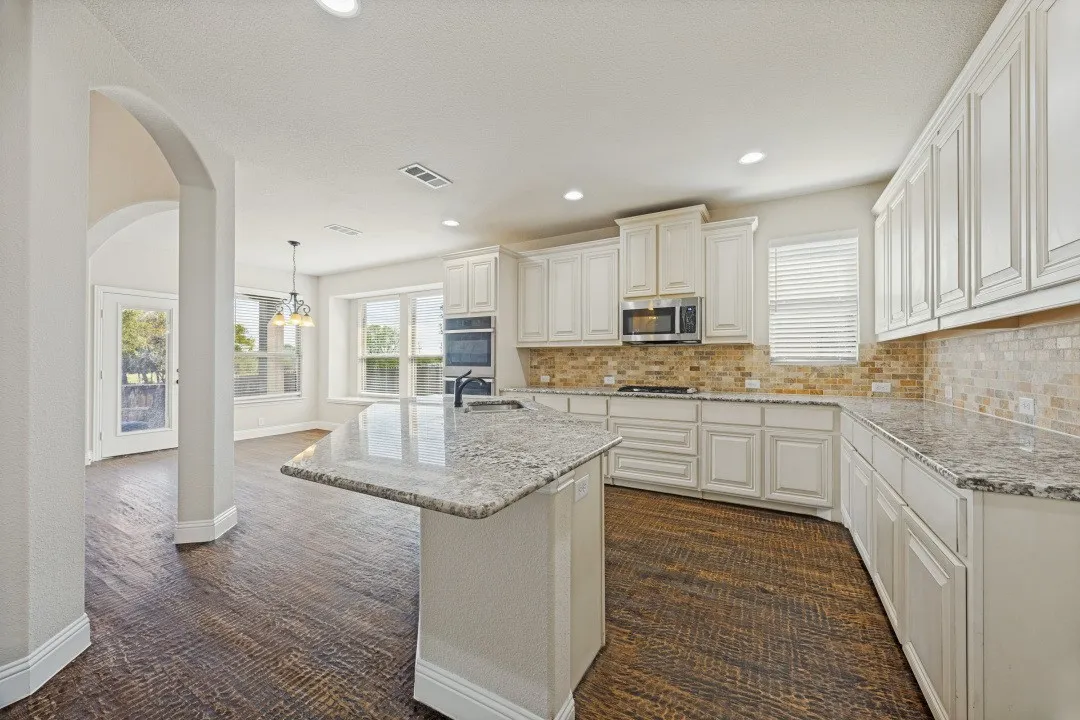 Kitchen featuring white cabinetry, light-toned countertops, a tile backsplash, and stainless steel appliances