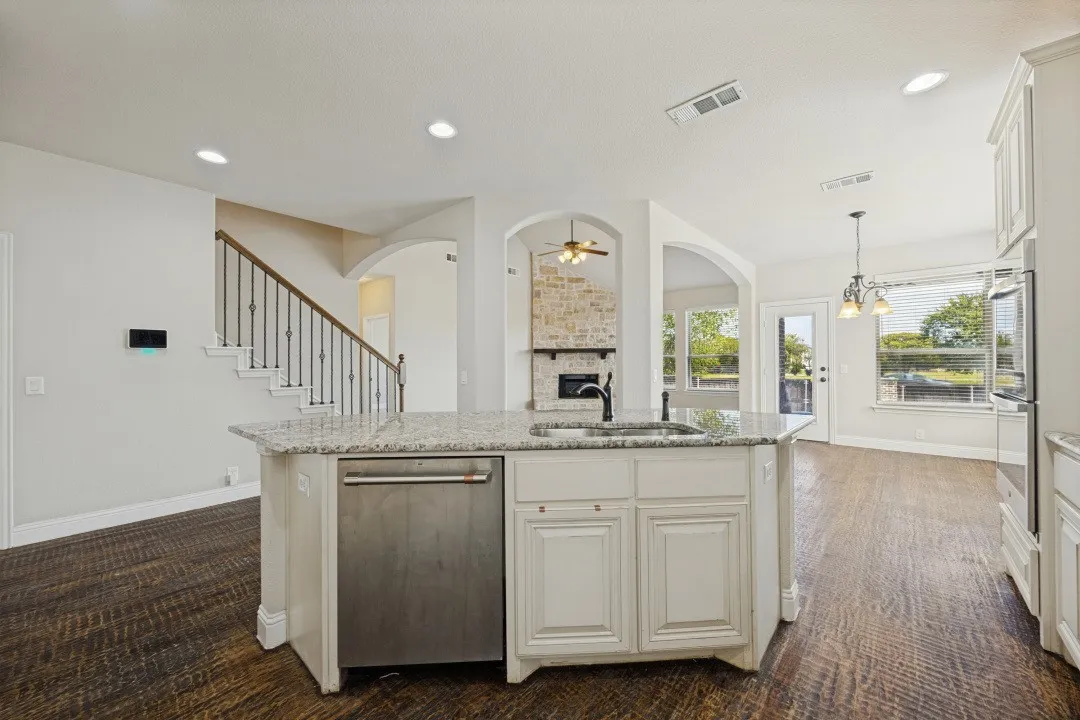 Kitchen island with granite countertop, stainless steel dishwasher, and undermount sink