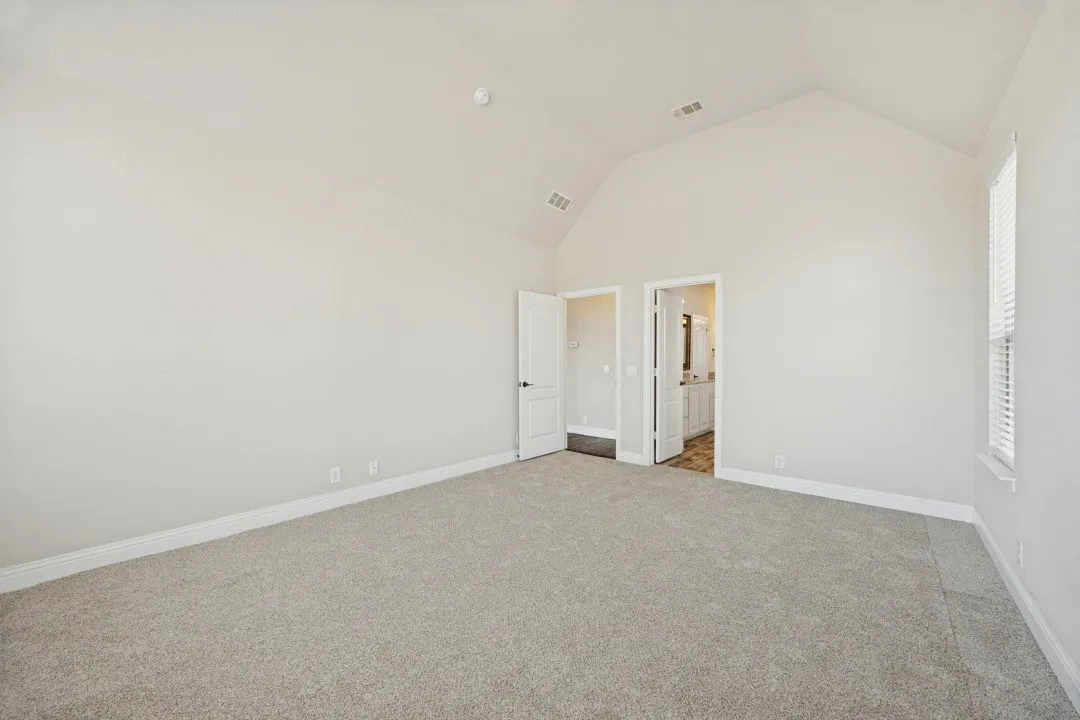 Vaulted ceiling, neutral wall paint, carpet flooring, window with blinds, and white trim