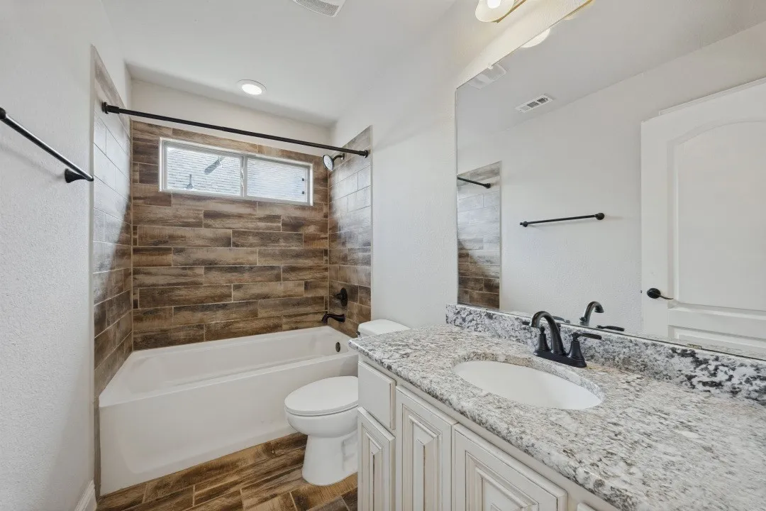 Bathroom featuring a white vanity with a granite countertop, undermount sink, and black fixtures
