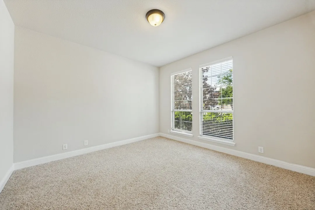 Neutral wall finishes, carpeted flooring, and two windows with blinds