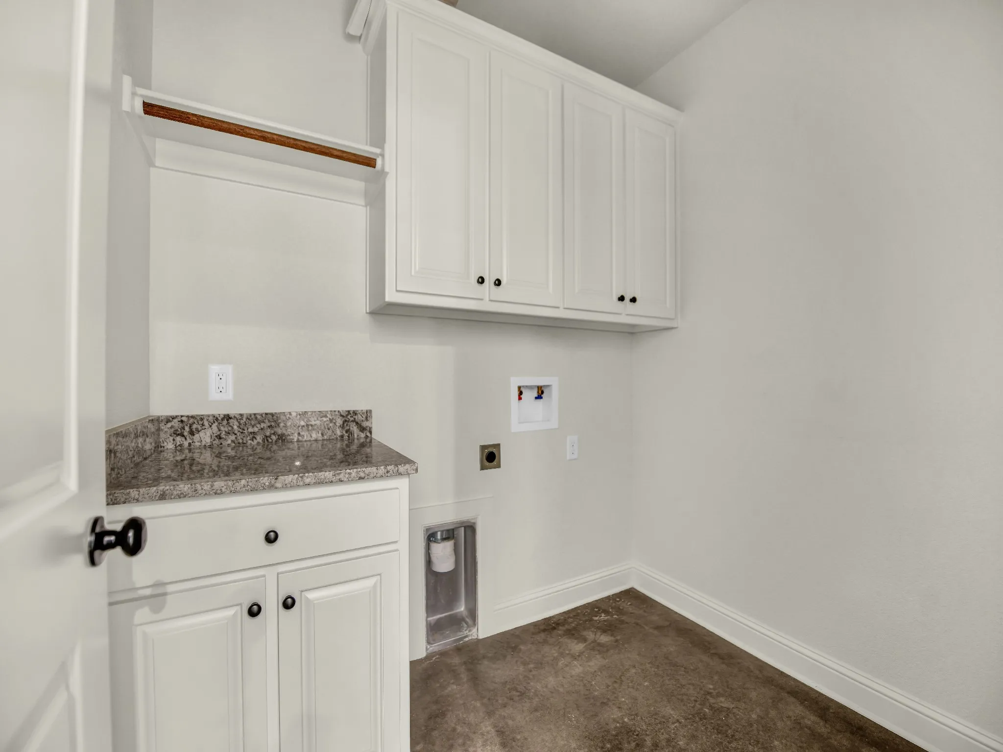Spacious laundry room with granite countertops, ample storage, and enough space for full size washer and dryer.