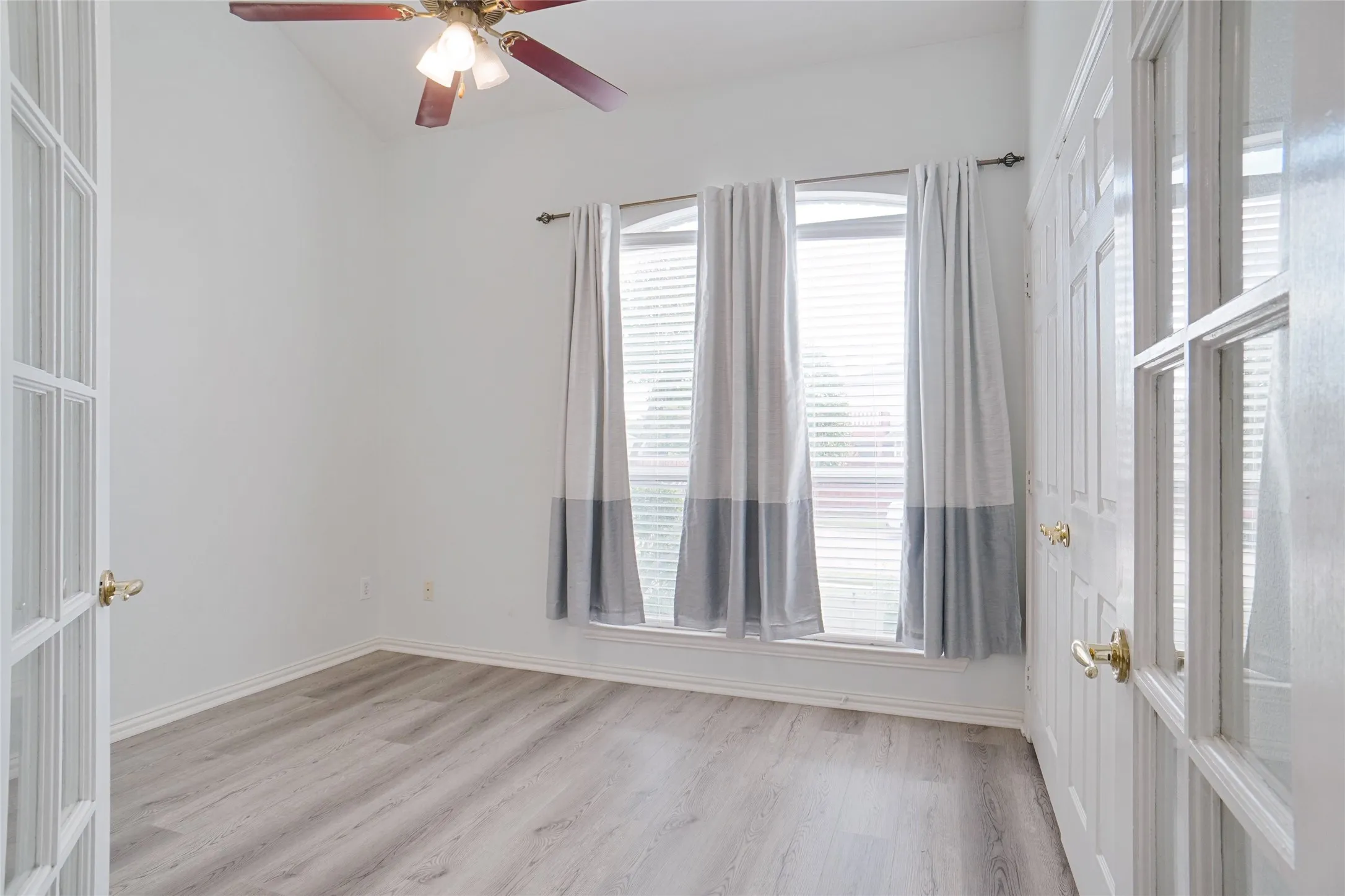 Empty room with light wood-style flooring and ceiling fan