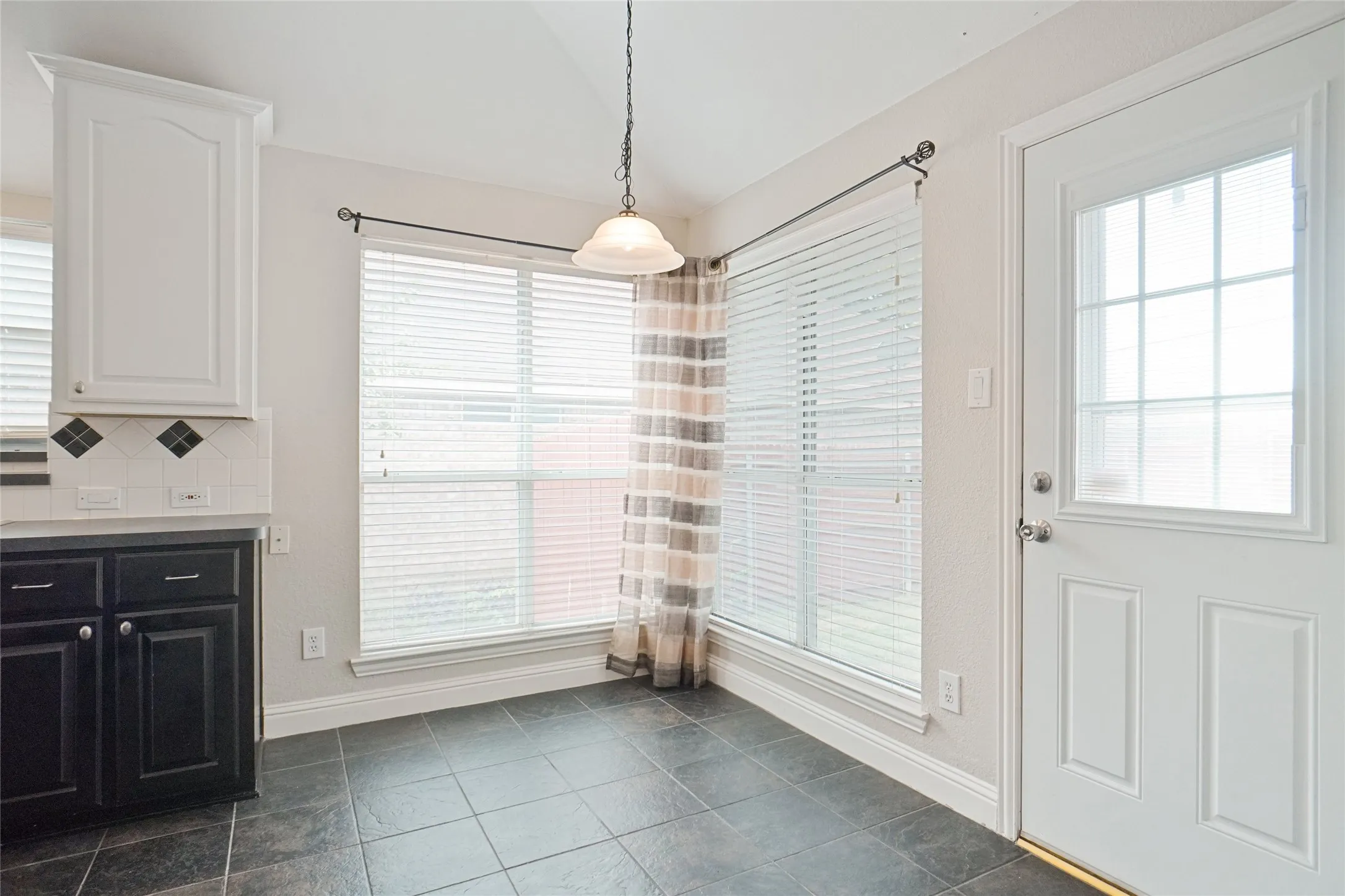 Unfurnished dining area featuring dark tile patterned floors and lofted ceiling