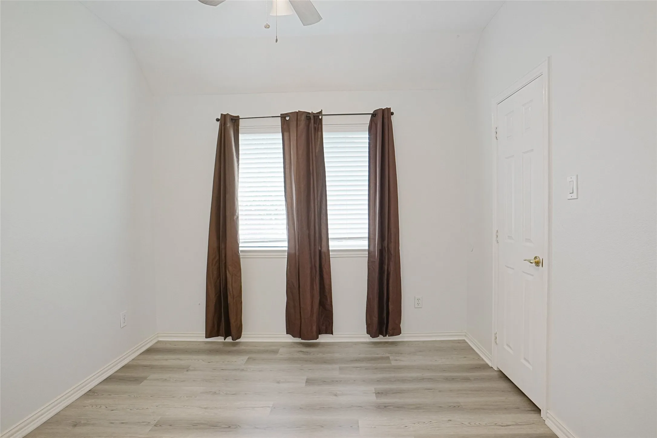 Unfurnished room featuring light wood-style floors, vaulted ceiling, and ceiling fan