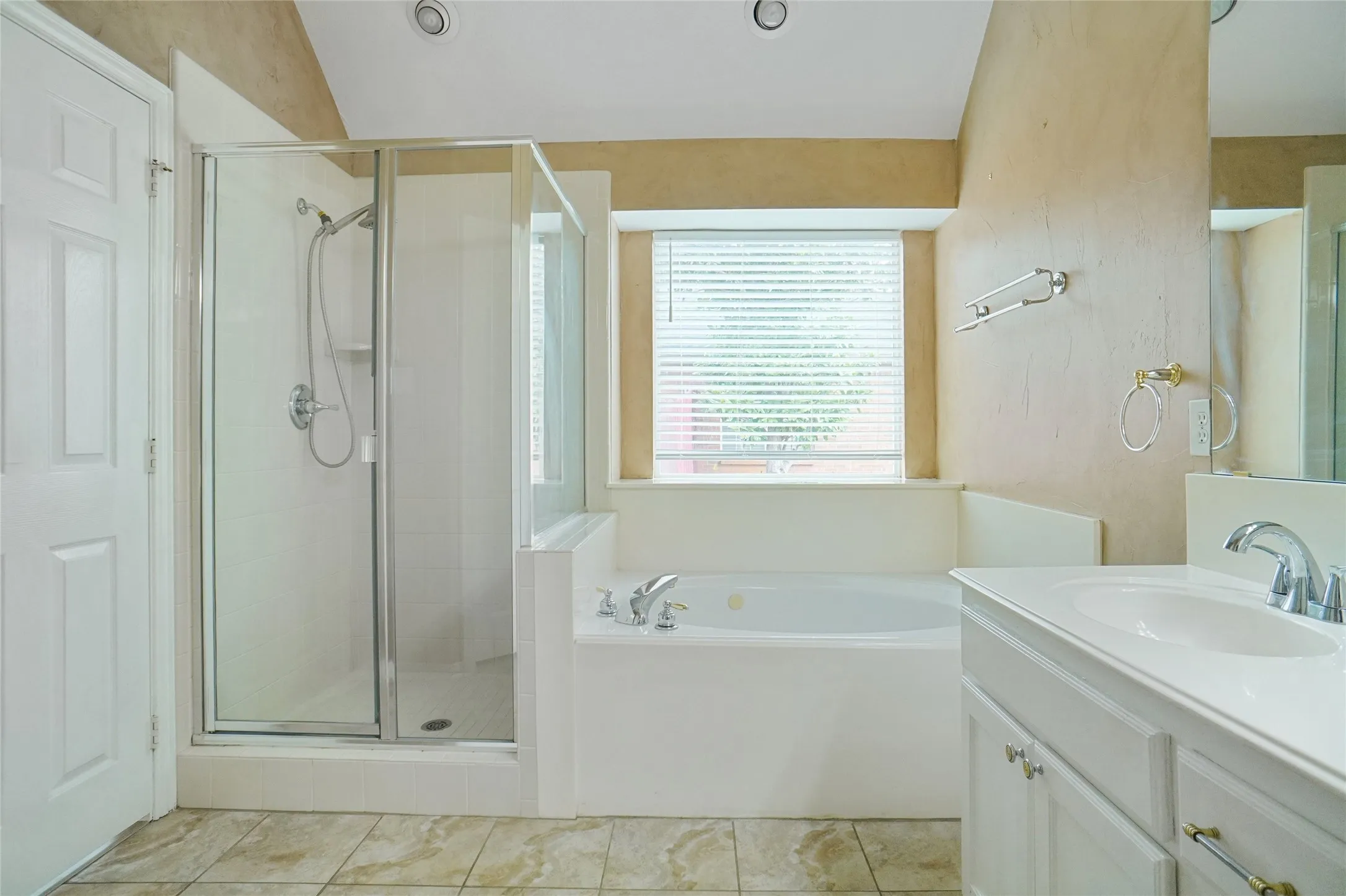 Bathroom with a shower stall, vanity, a garden tub, light tile patterned floors, and lofted ceiling