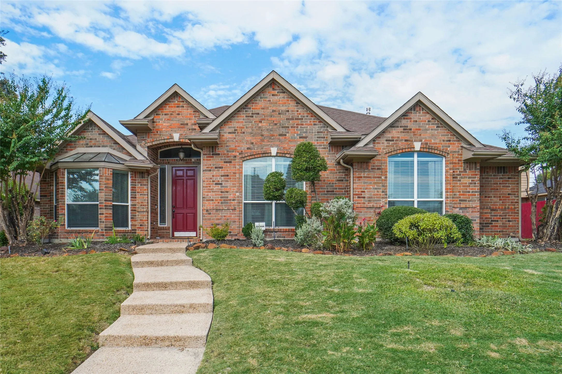 View of front of house with a front lawn, brick siding, and roof with shingles