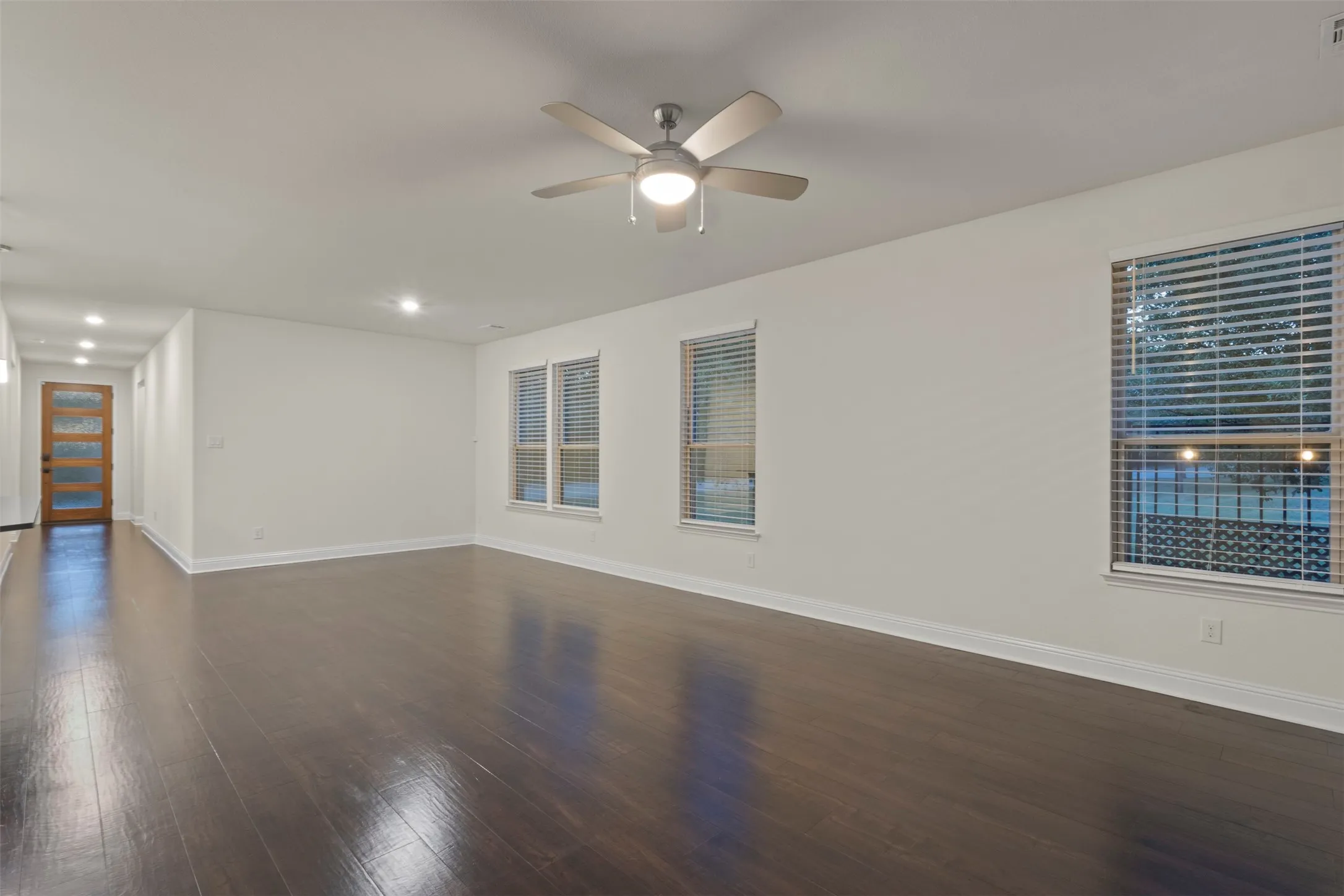 Dark wood-finish flooring, recessed lighting, and a ceiling fan with integrated lighting
