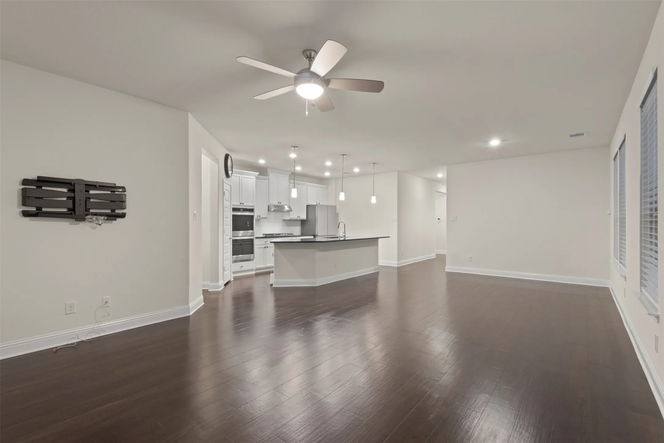 Spacious living area featuring wood-finish flooring, recessed lighting, and a ceiling fan